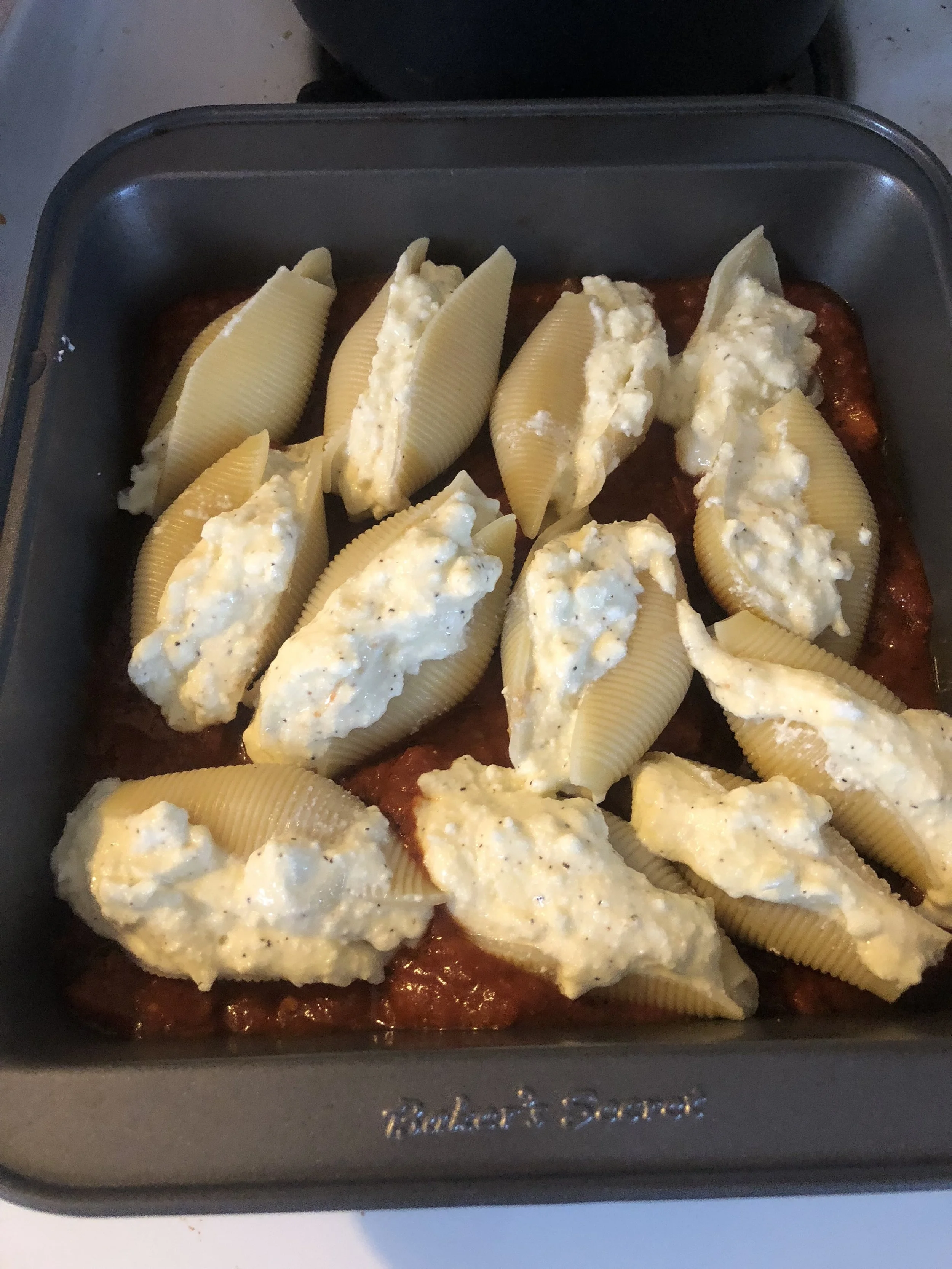 Using your hands and your spoon, individually stuff each shell and carefully place them on the bed of sauce. This pan held 13 shells comfortably - I don't have many baking dishes! I am still stocking my kitchen!