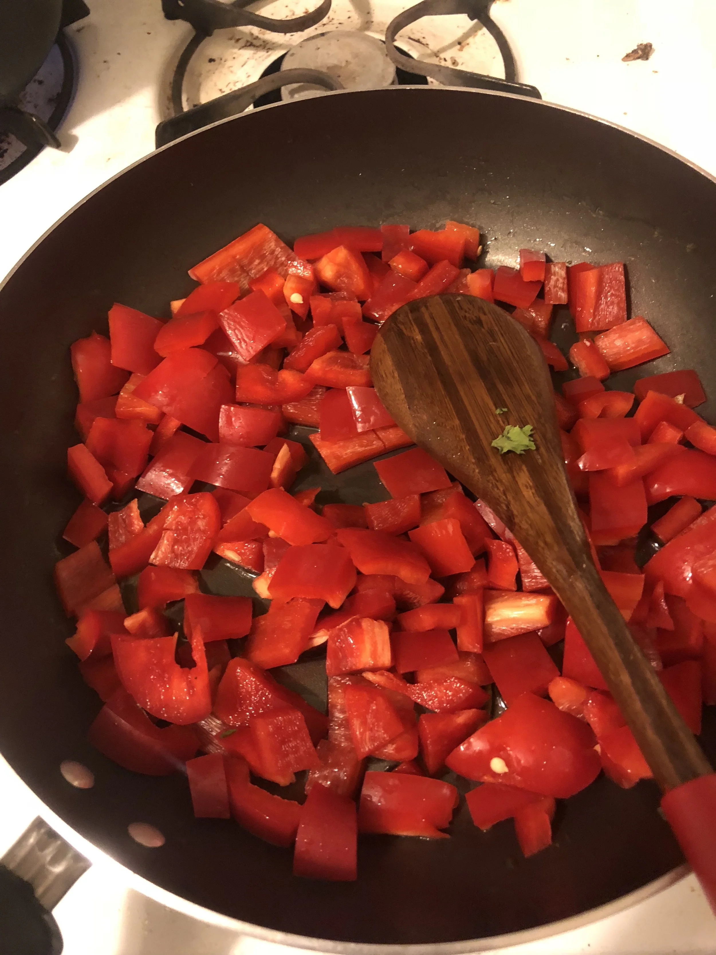 Add the red peppers to the pan and cook on medium high heat, stirring frequently. While peppers cook, dice inions and garlic.