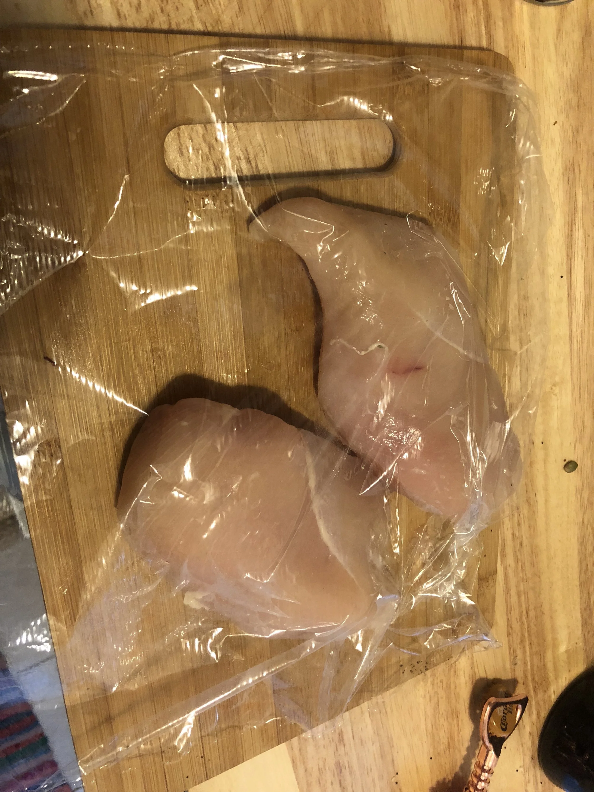 Clean your chicken breasts and cover with a piece of plastic wrap Using your meat mallet, heavy but of knife, or if you're a little bit innovative like this lady, your hammer, flatten the chicken breast to about 0.7-0.5 inches in depth.