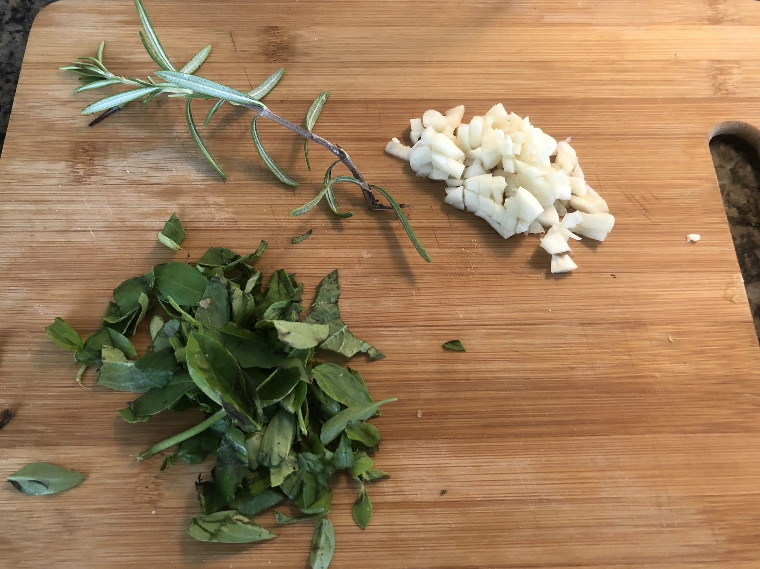 Chop the basil and garlic. Remove the leaves from the rosemary and chop. Add olive oil to your medium skillet.