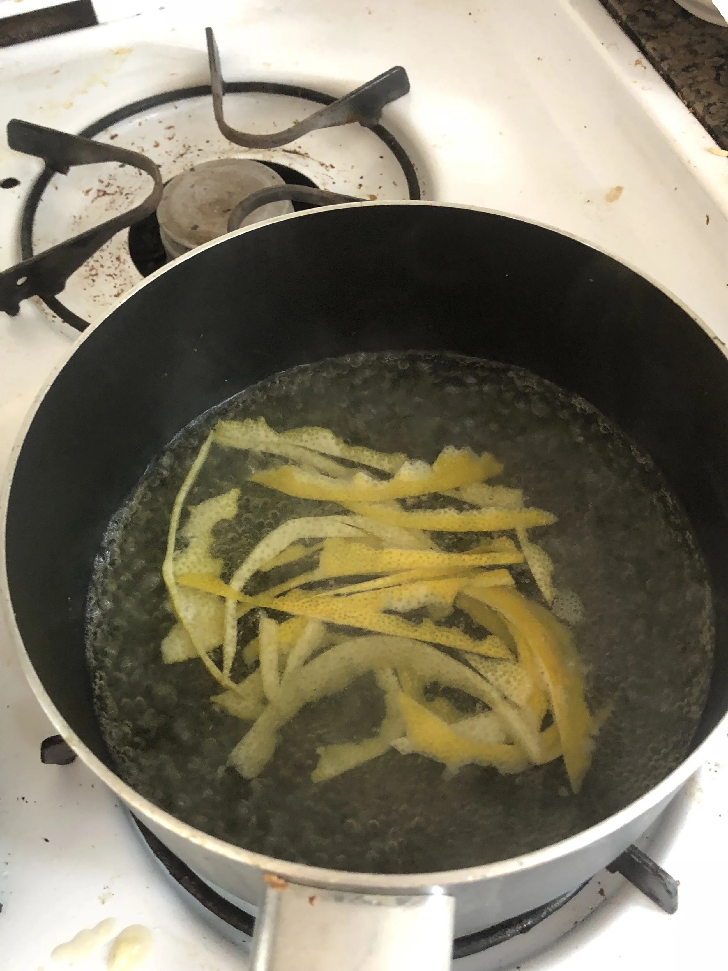Add two cups of water to your medium saucepan, bring it to a boil with the peels inside. When it has boiled for 2 minutes, drain the saucepan. Add 2 more cups of water to the saucepan, and boil the water, with the peels in it, until it has boiled quickly for 2 minutes. Carefully drain your saucepan. Add 2 more cups of water to the saucepan and boil the water, with the peels in it, until it has boiled quickly for 2 minutes. Carefully drain your saucepan. Take the peels from the pot and put on a paper towel. Add 2-3 cups of water to the saucepan and your cup of sugar. Boil the water on medium heat until the sugar dissolves, being careful to sit constantly. When the sugar has dissolved, add the peels into the saucepan. As the water cooks off, simple syrup will be created. Cook the peels for 5-15 minutes in the saucepan, and keep checking.stirring the pot while it is on heat. Remove the peels, carefully, and then when cool, toss them in granulated sugar. Refrigerate and then use however works. *I added a sprig of Rosemary into my simple syrup and din't cook all the way down to make actual simple syrup but I was in a time crunch. 