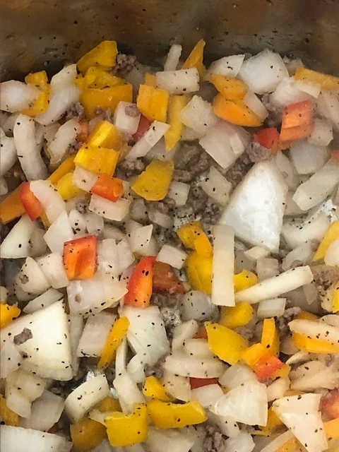 Add olive oil to the stockpot from the beef and then add the onions and peppers. Season your aromatic vegetables with salt and pepper and cook 5-6 minutes. When aromatic, add the beef, spices, chicken stock