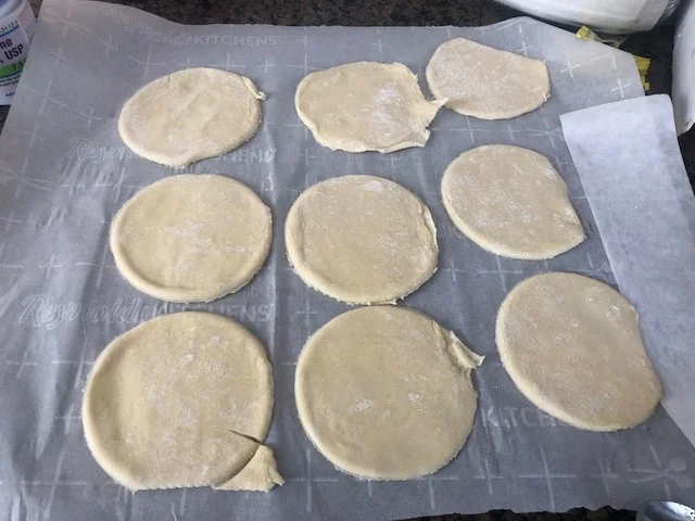 Preheat the oven to 370 degrees. Open your pastry sheet and cut out your empanada shapes. Your pastry dough should have been defrosting for apx 40 minutes. spoon your tsp of fill-ins to the left side of every empanada shape
