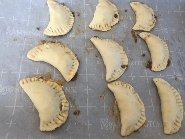 Fold over your empanada shapes and seal with your fork as you would with ravioli. Put them in the oven for 9 minutes with the sheet pan in and then take your pan out and put the opposite side in, and cook for 5-6 more minutes.