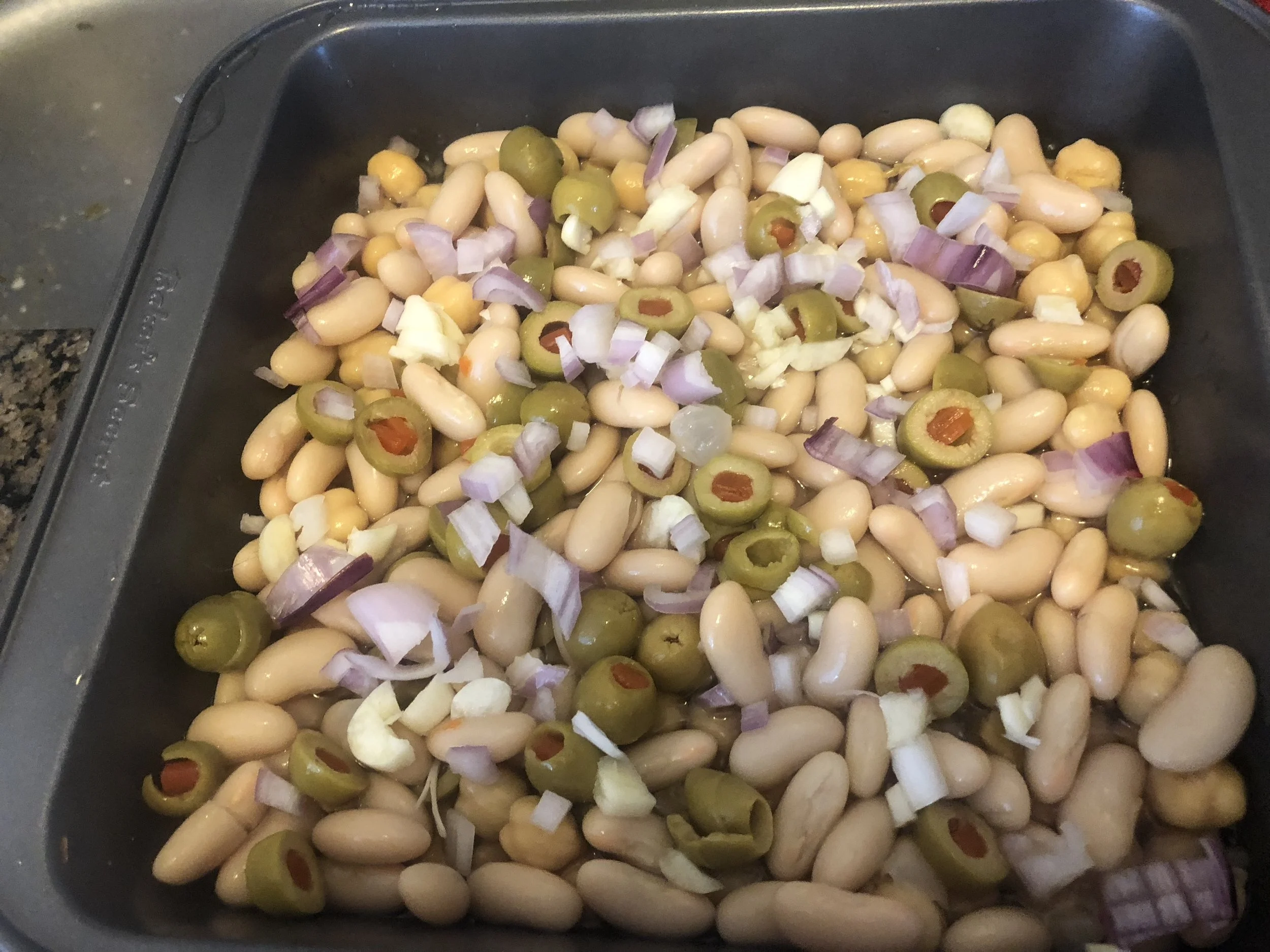 Preheat the oven to 325 degree Mix the coined olives, shallots (with some reserved) and the beans and pour over the bottom of the pan. Pour in 0.25 cup of water