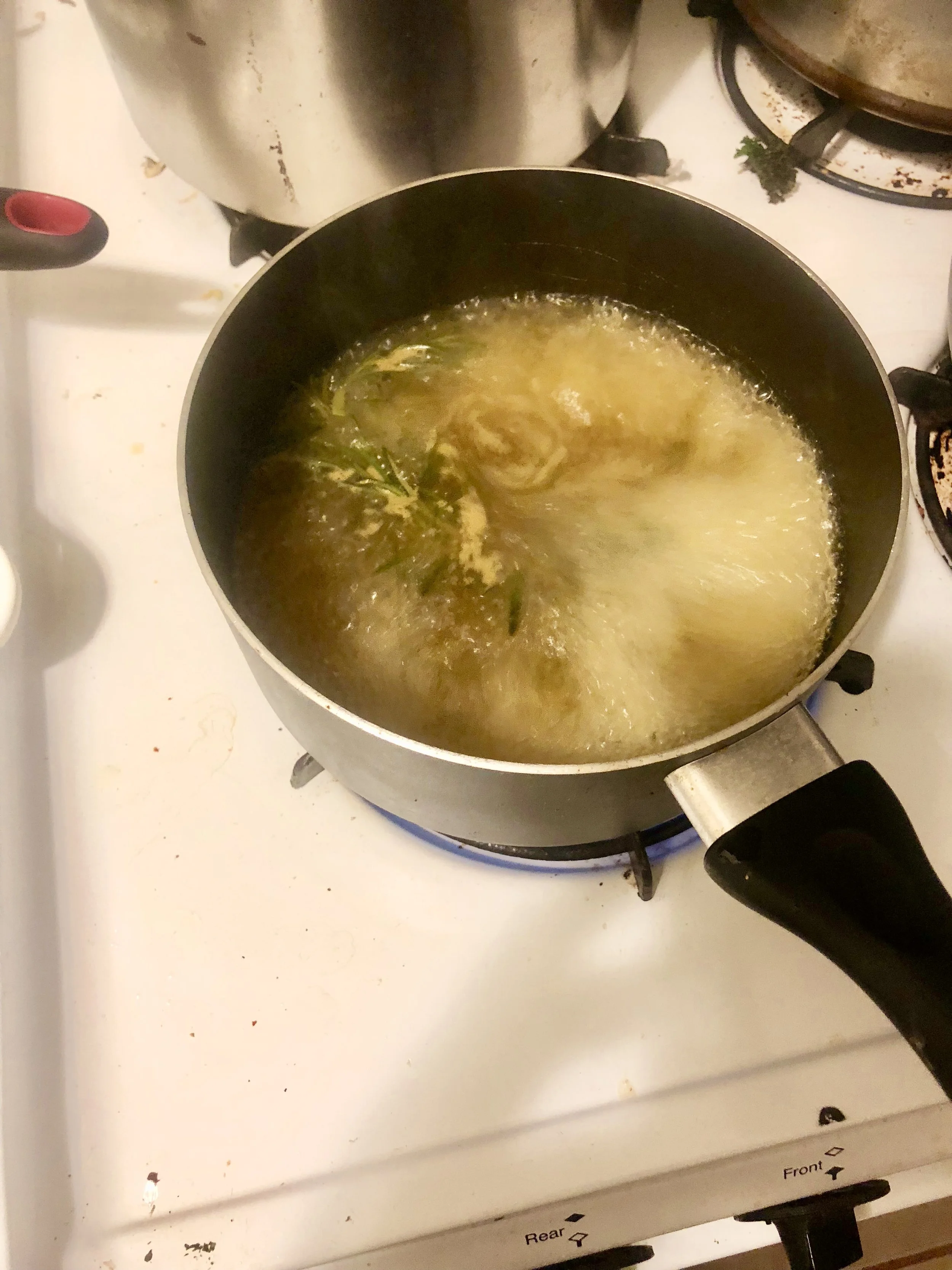 While the tomatoes are cooking, make the stock. Combine chicken stock, herbs, a clove of garlic into your medium saucepan, and cook until integrated.