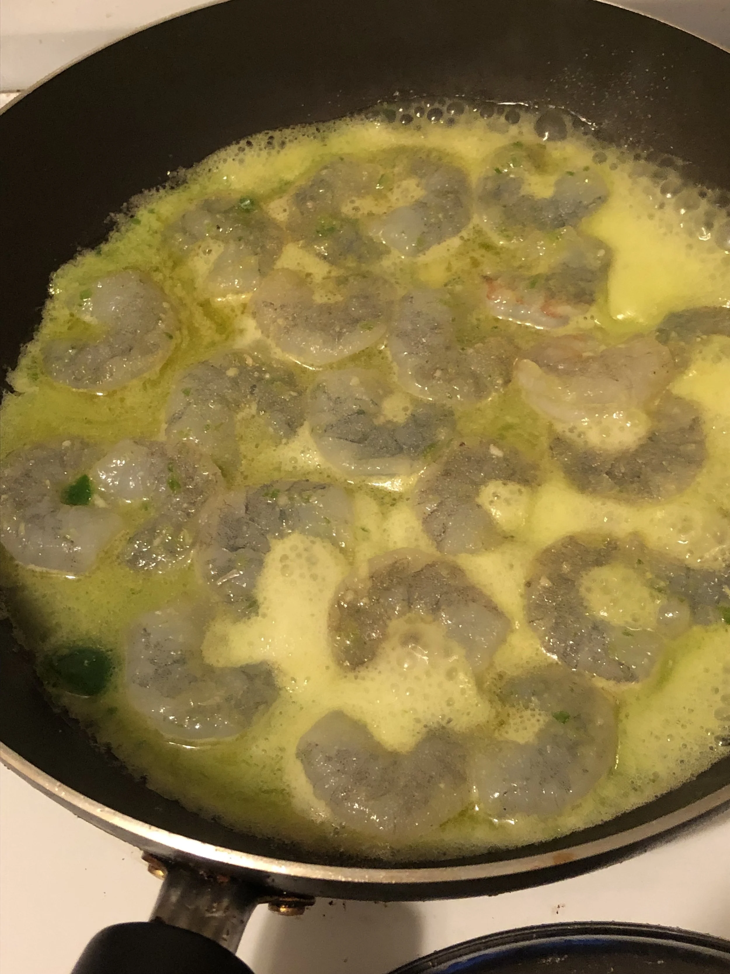 Add the remaining oil to the pan and when medium hot, add the shrimp and a little bit more than half of the marinade. Cook the shrimp until they are cooked both sides. As the sauce cooks down it will become more aromatic and when the shrimp is almost done cooking add the peas, stirring to mix them in. Sprinkle the chopped basil leaves over the top of the dish when the peas have cooked. . I