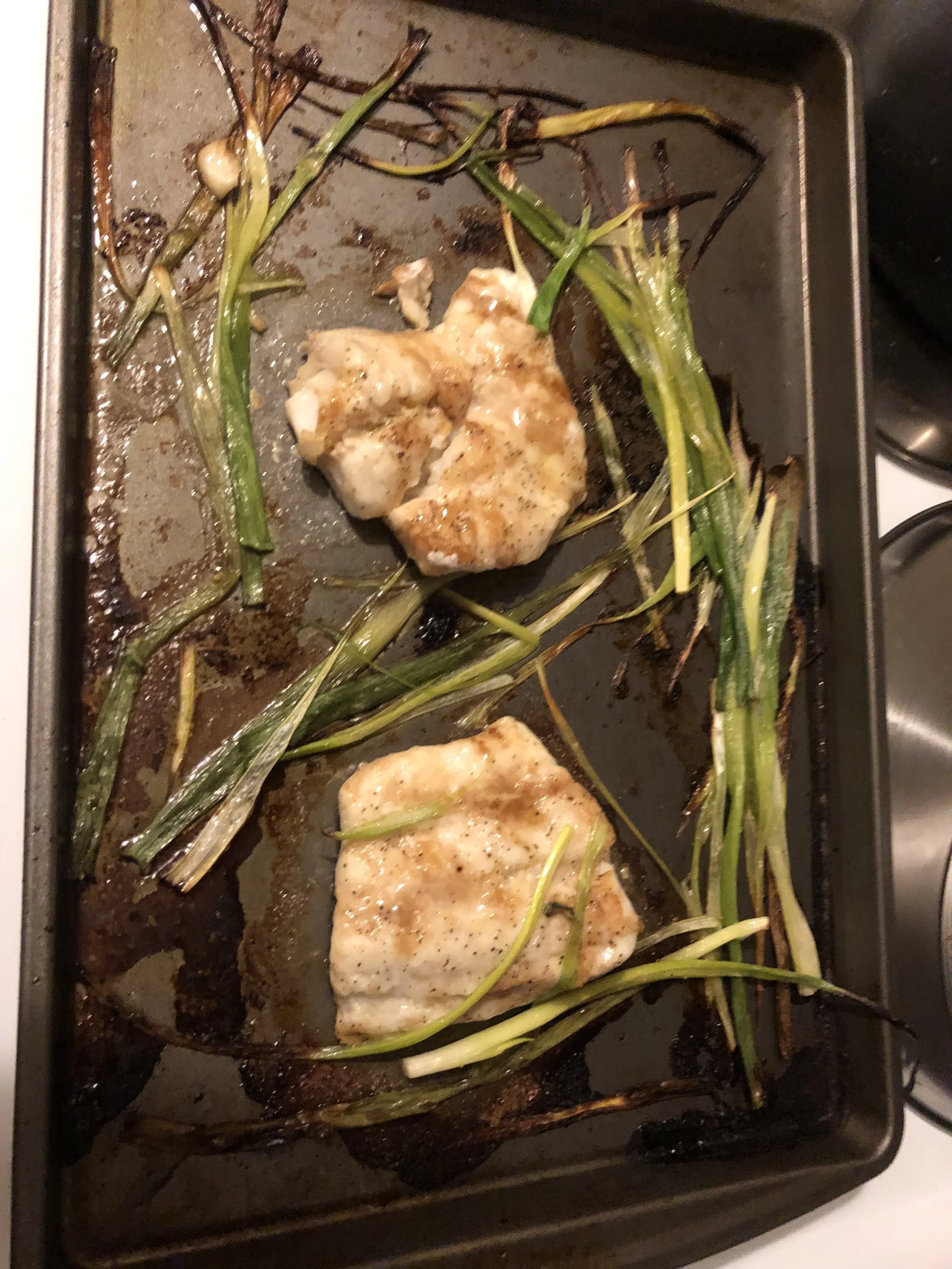 Remove the pan when the fish flesh is baked but still tender and the scallions are cooked with crispy charred parts. The fish should have cooked between 13-15 minutes. Serve the fish hot, covered in the yogurt sauce, and with sides of your preference, A beautiful serving suggestions would be serving the cod on top of a bed of the roasted scallions.