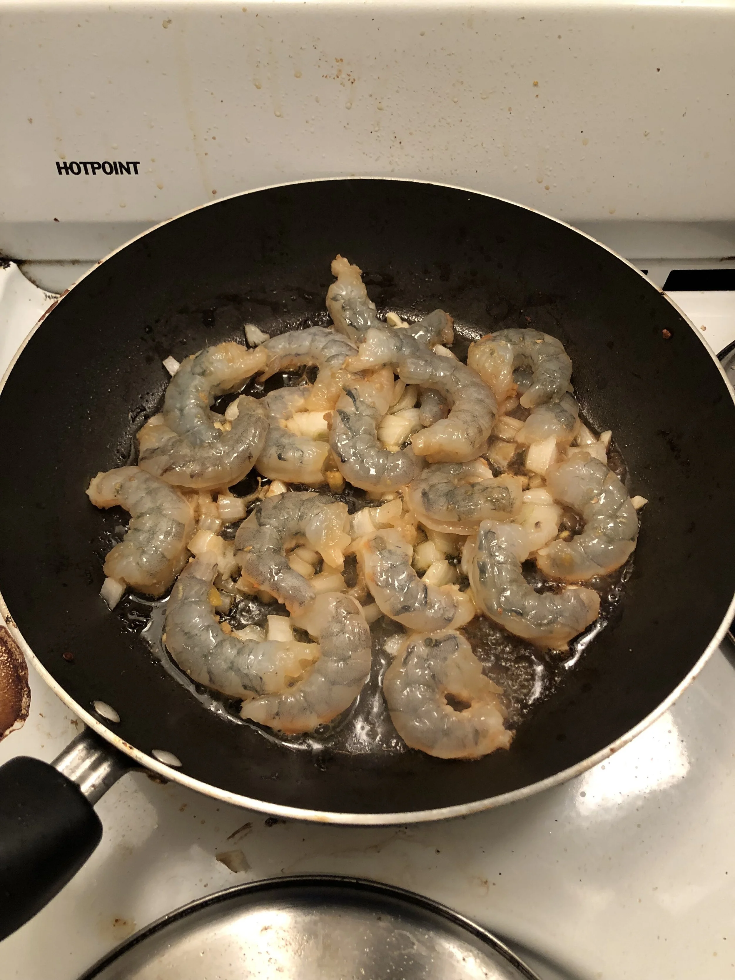 Add some diced onion/shallot and 3 garlic cloves (diced) to the drippings from the same pan and when aromatic, add the shrimp to the pan. Cook the shrimp until done (salmon color on both sides). Remove the shrimp from the pan and put on the pineapple plate.