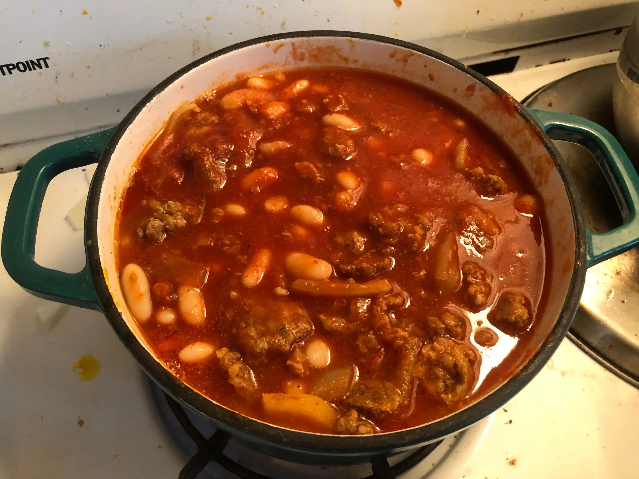 Add the beans, the tomatoes, and the sausage back into the pot and cook for 30-40 minutes with the top on. It should not be boiling but it should still be actively cooking. You are looking for the flavors to integrate. Serve hot with cheese (shredde…
