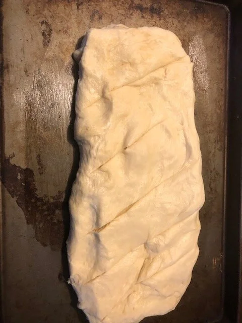 Punch it down and form it into a loaf on a greased cookie sheet. . Make 5 slashes across the top. Cover.