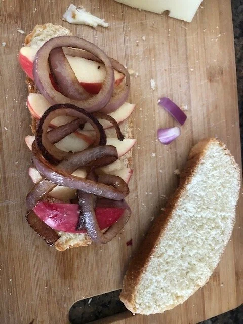 Off a crusty loaf (I used the day old loaf previously featured in this blog) cut two healthy slices, not thick but substantial. Dress the bread with mustard (I used Dijon). Layer thinly sliced apples, carmelized onions. and then place over the onion…