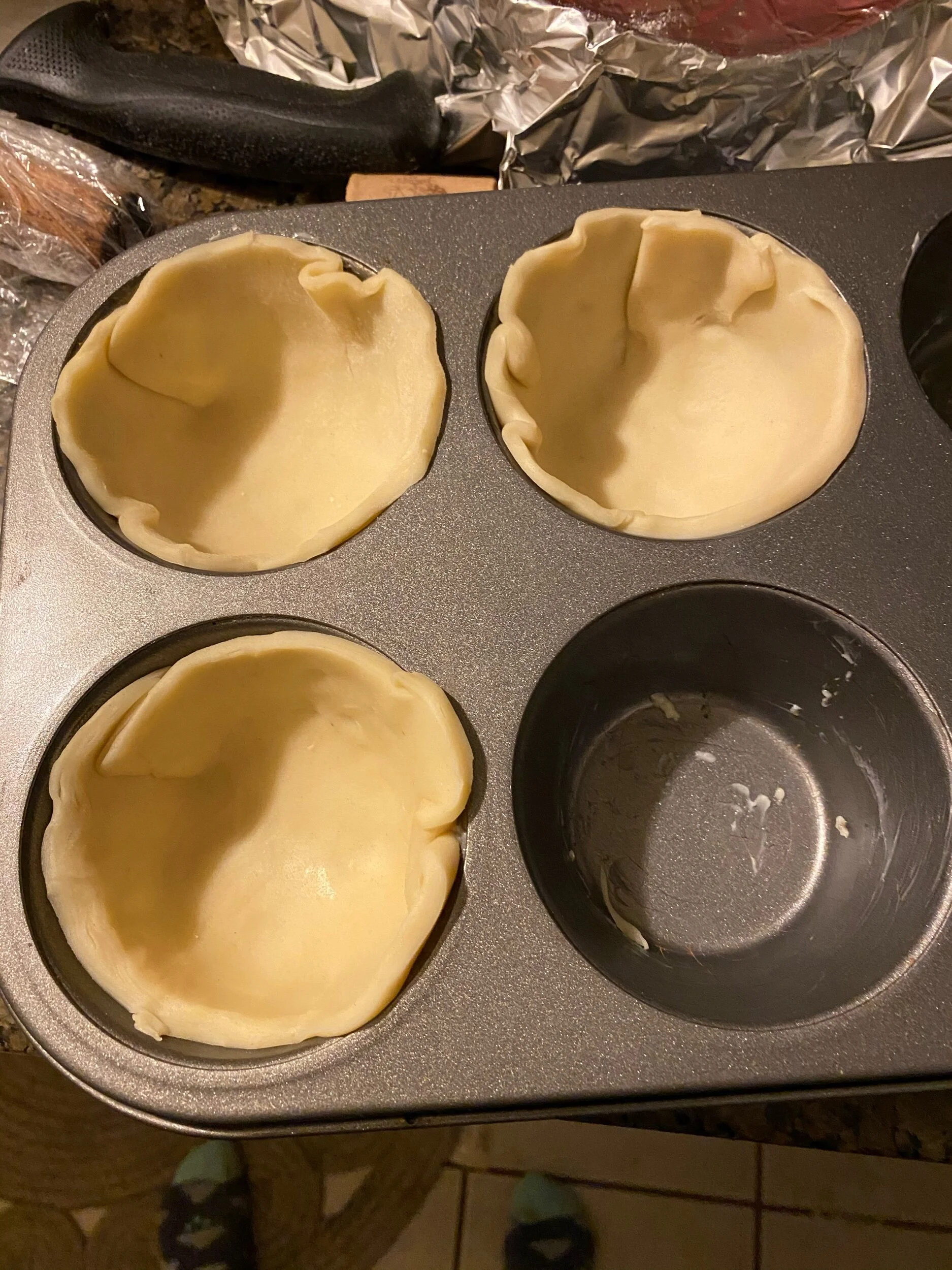 When your apples have cooled, GenerouslY butter your “6 muffin” Muffin tin. And roll out your pie dough. Trace a big mug or sm bowl for the bottom crust and press it into the tin, making sure the edges come all the way to the top.