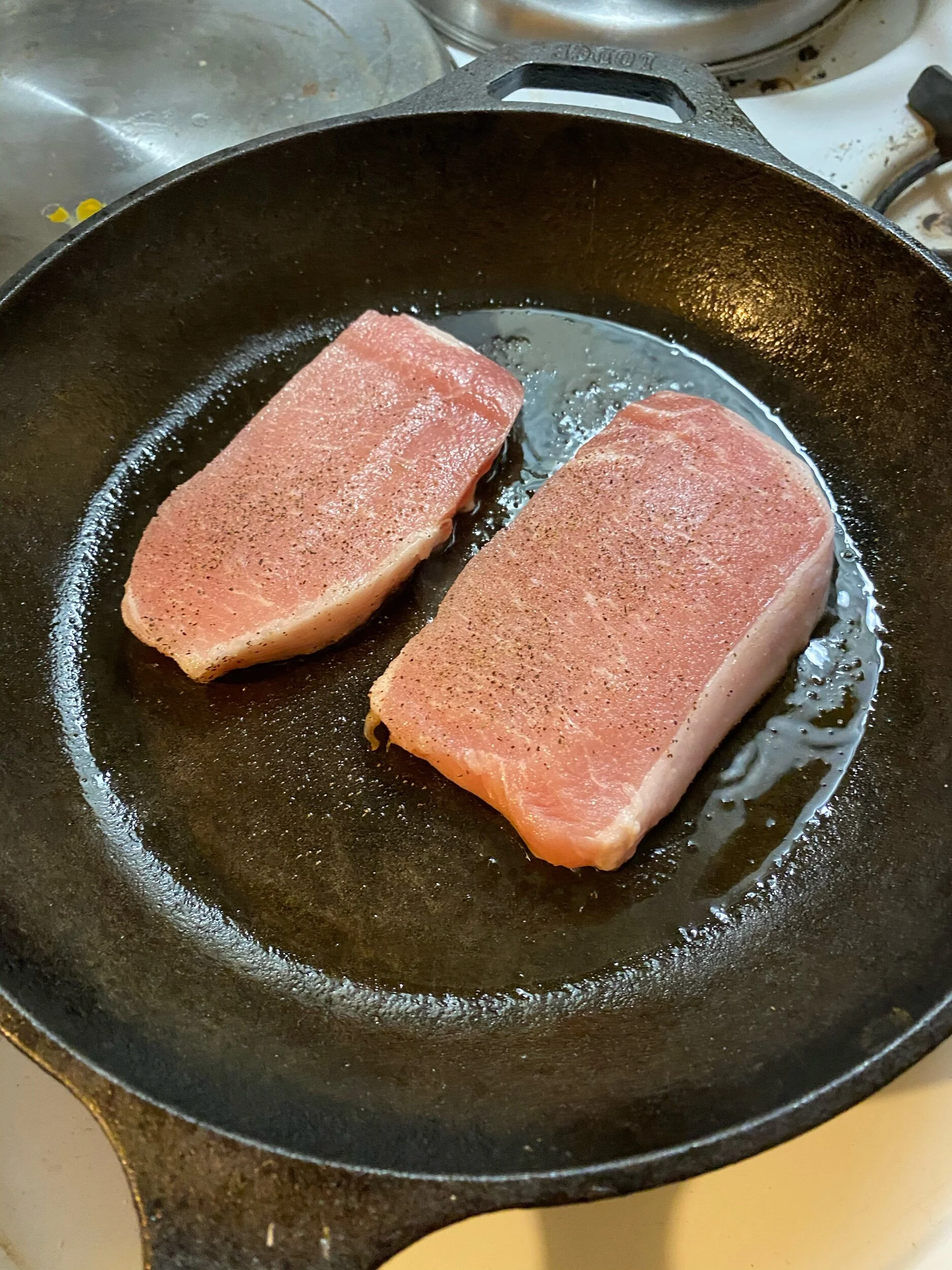 Preheat the oven to 350 degrees (and make sure to take all your pots and pans out of it, if you’re like me and storage is at a premium). Generously season both sides of the pork chops with salt and pepper and heat the olive oil in your cast iron ski…