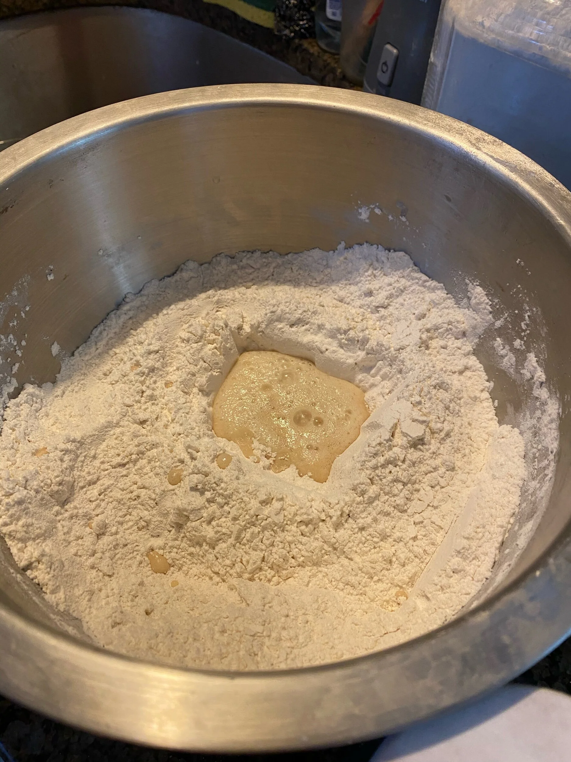 Mix the flour and salt in your massive mixing bowl. Folks, let’s face it-  6 cups of flour is no sm amount of flour so give yourself some room to mix without spilling flour all over your kitchen. Make your own well in the flour with your fingers, an…