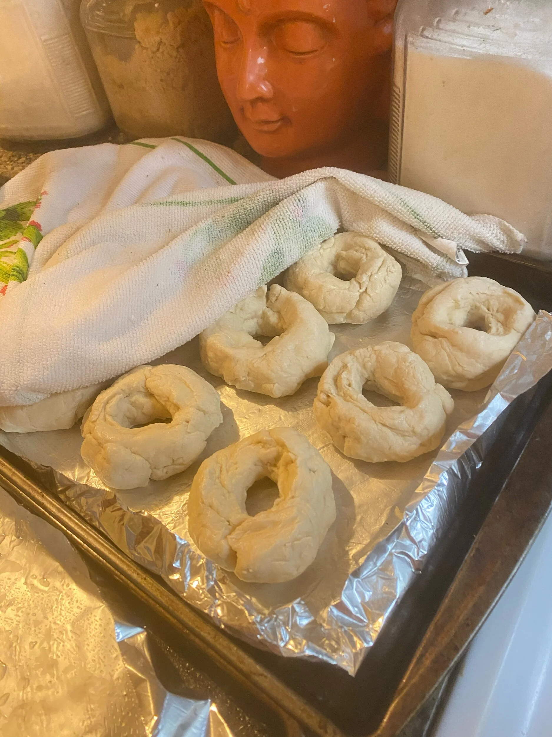 I did the easy thing, stuck my fingers through the center and made bagel shapes. True bakers apparently make the balls into snakes of dough, and then loop them around their hands, twisting the edges together. I did not do the best job kneading them,…