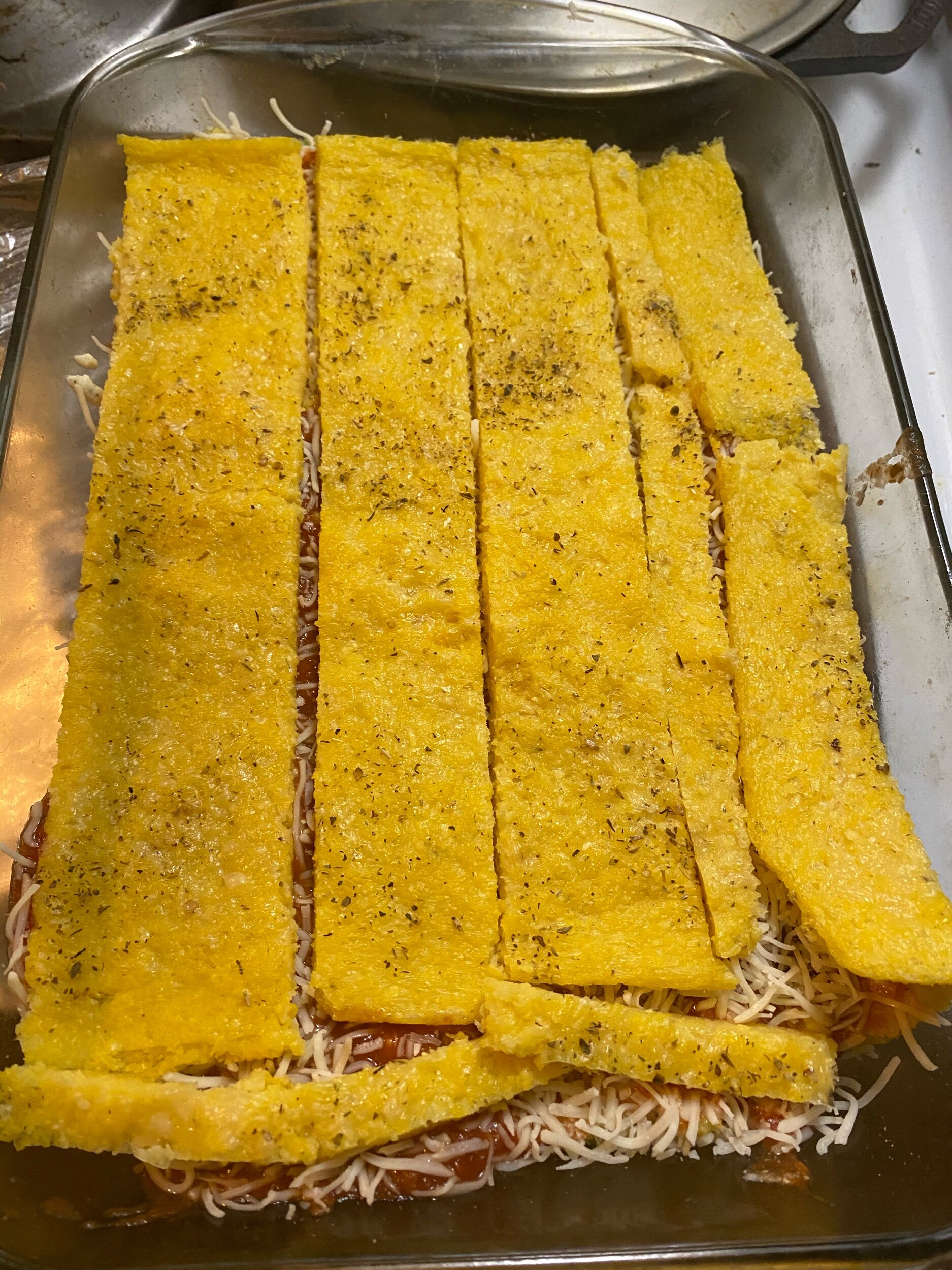 Cover the mozzarella with another layer of polenta strips. Cover with another layer of ricotta, sauce, and mozzarella cheese. Sprinkle with some more Parmesan and place in the oven.