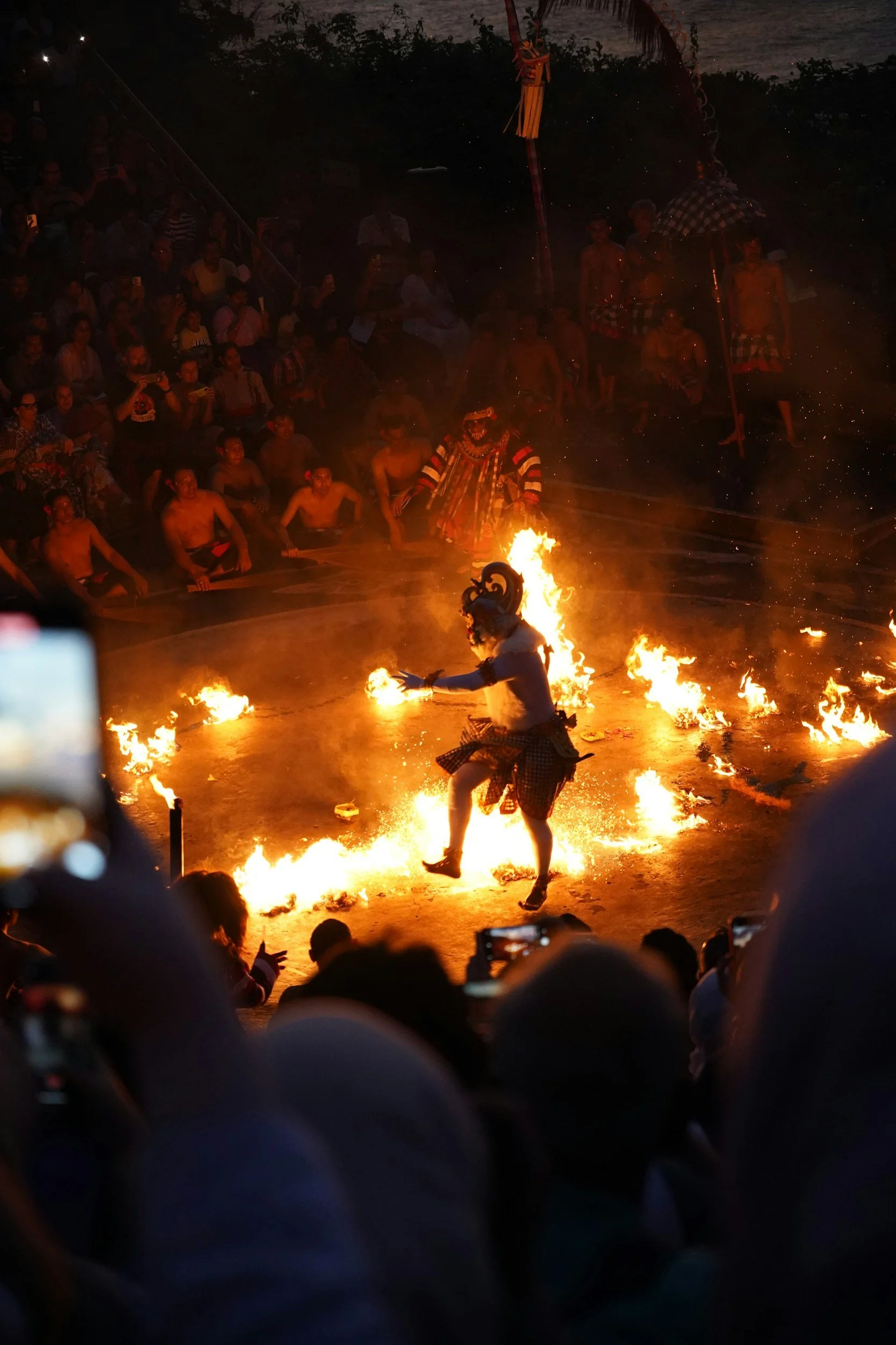 Masked dancer moving through the flames during the Kecak fire dance at Uluwatu Temple, Bali