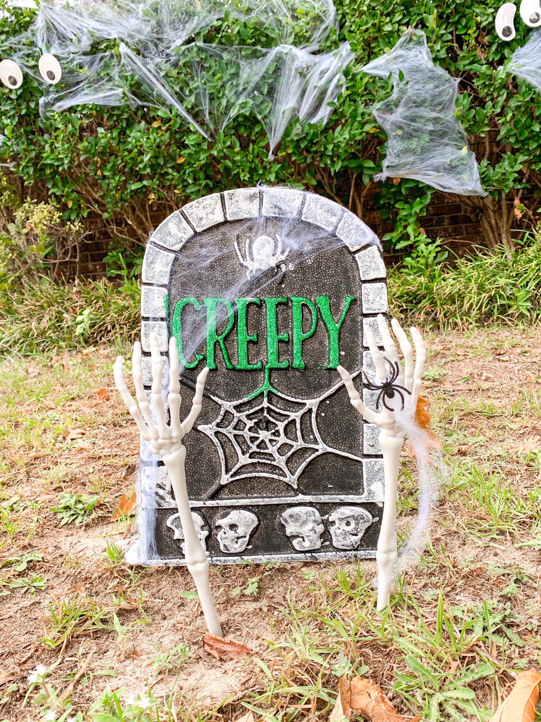 My favorite easy affordable Halloween decoration from the Dollar Tree!! $1 styrofoam gravestone , $1 skeleton arms (actually tongs), $1 spider webbing with spiders. $3 is NOT a bad deal.