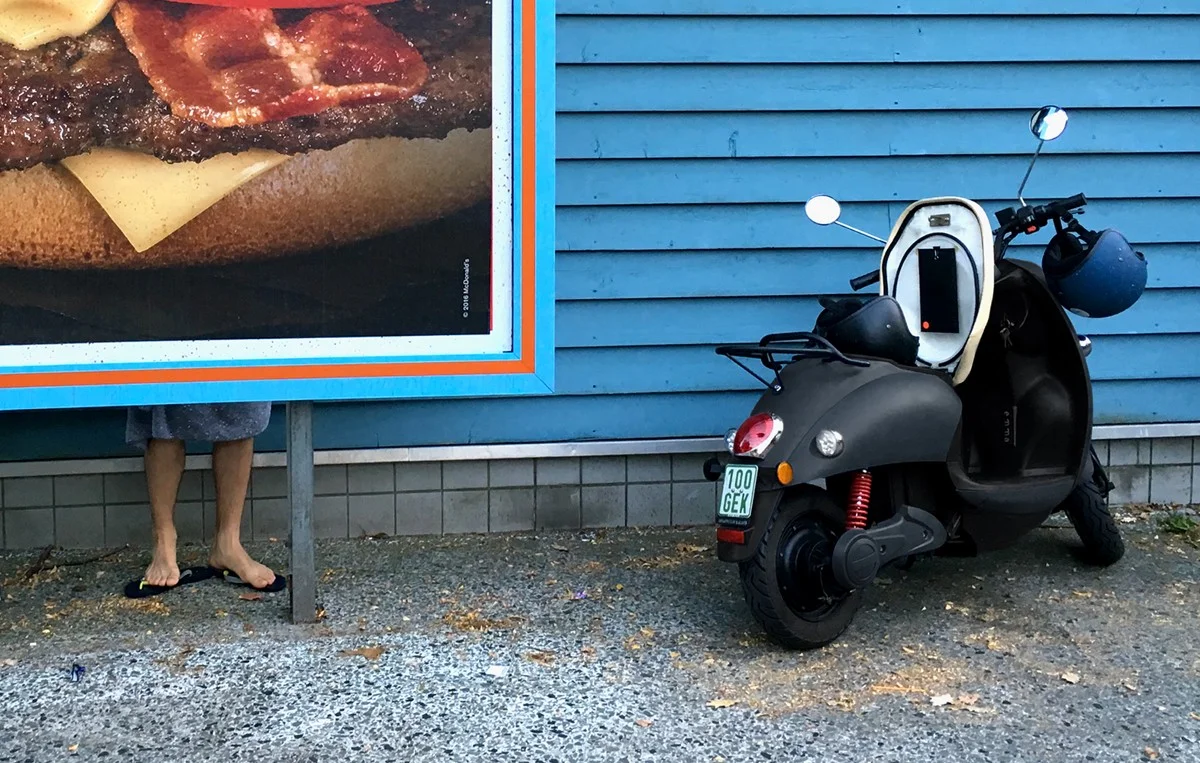 Mooi beeld van de unu scooter met een blauwe muur en hamburger poster op de achtergrond