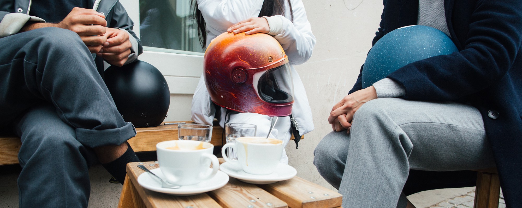 Vrienden die net van de elektrische scooter zijn afgestapt om met hun motorhelmen koffie te gaan drinken.