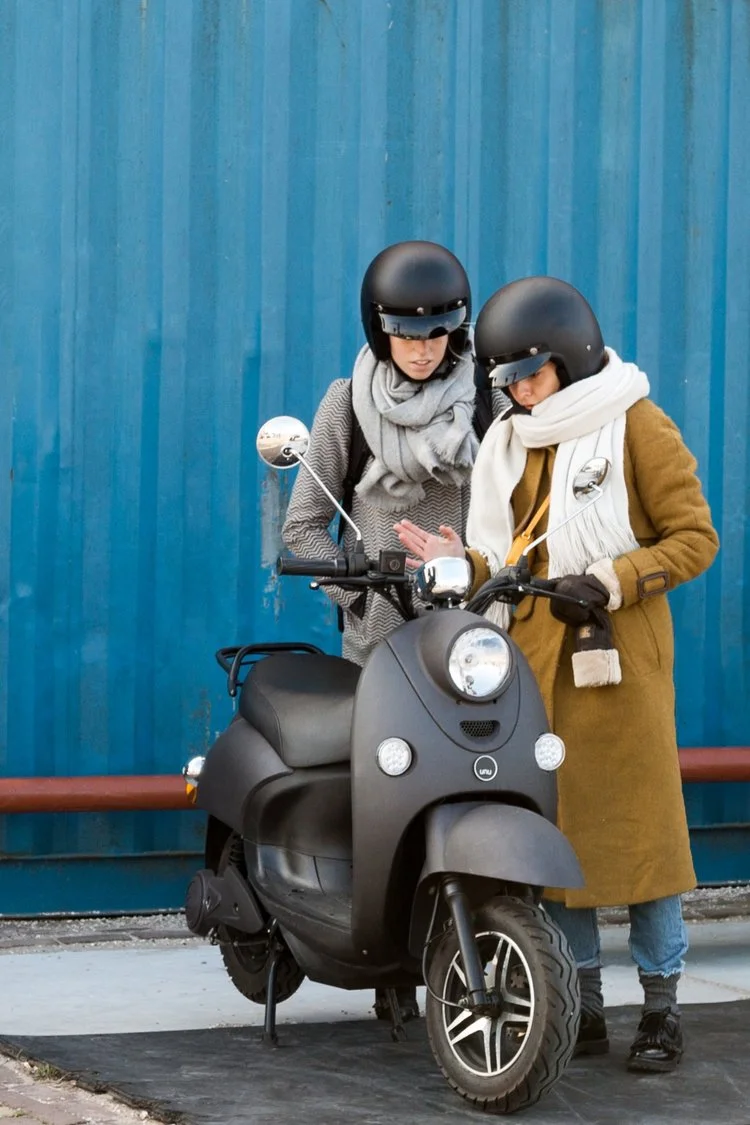 Unu midnight black scooter met twee scooterrijders ernaast.