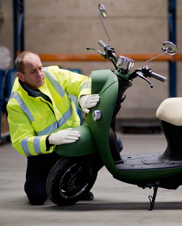 Man die een unu scooter controleert op foutjes