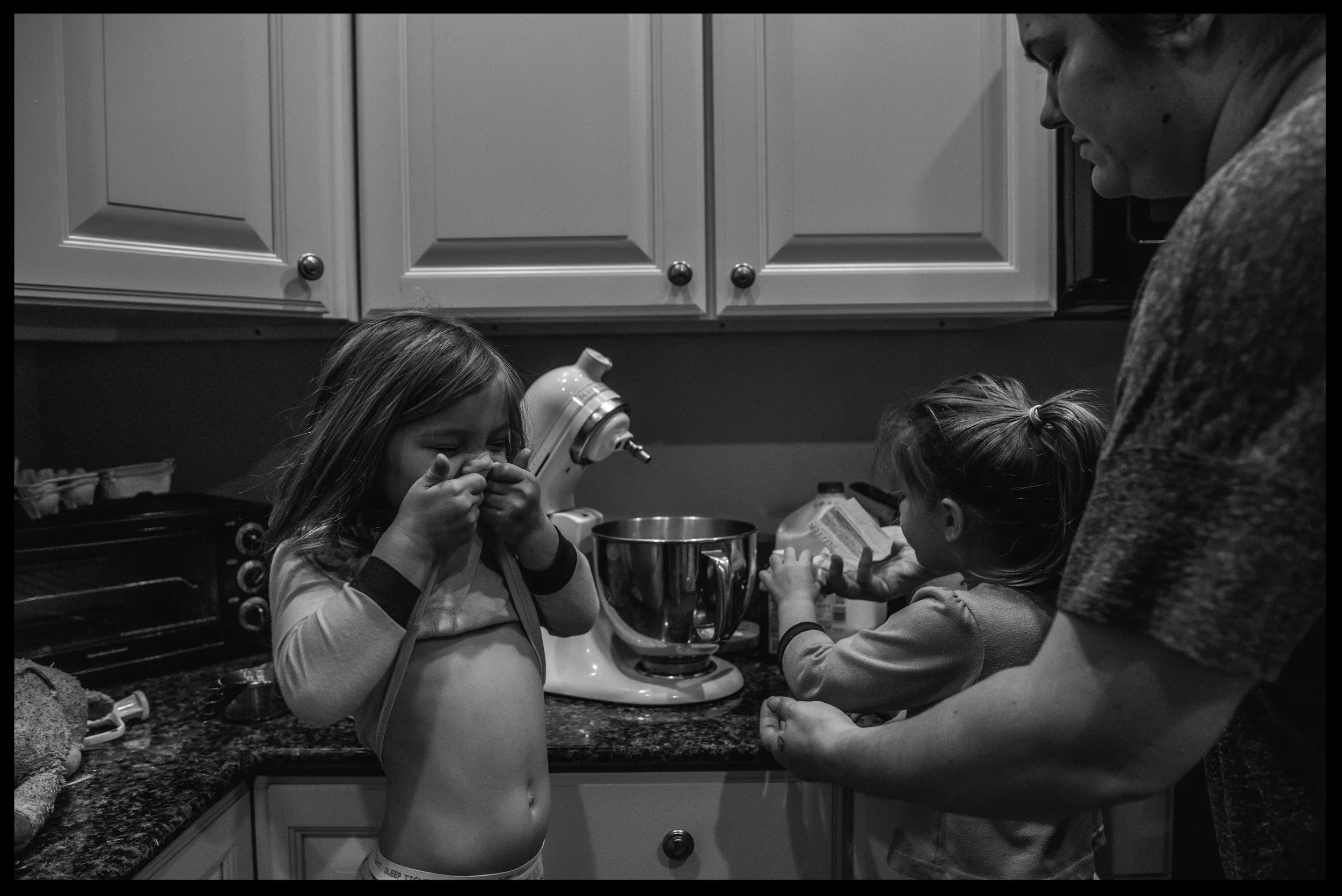 Daughters helping their mother make breakfast, black and white