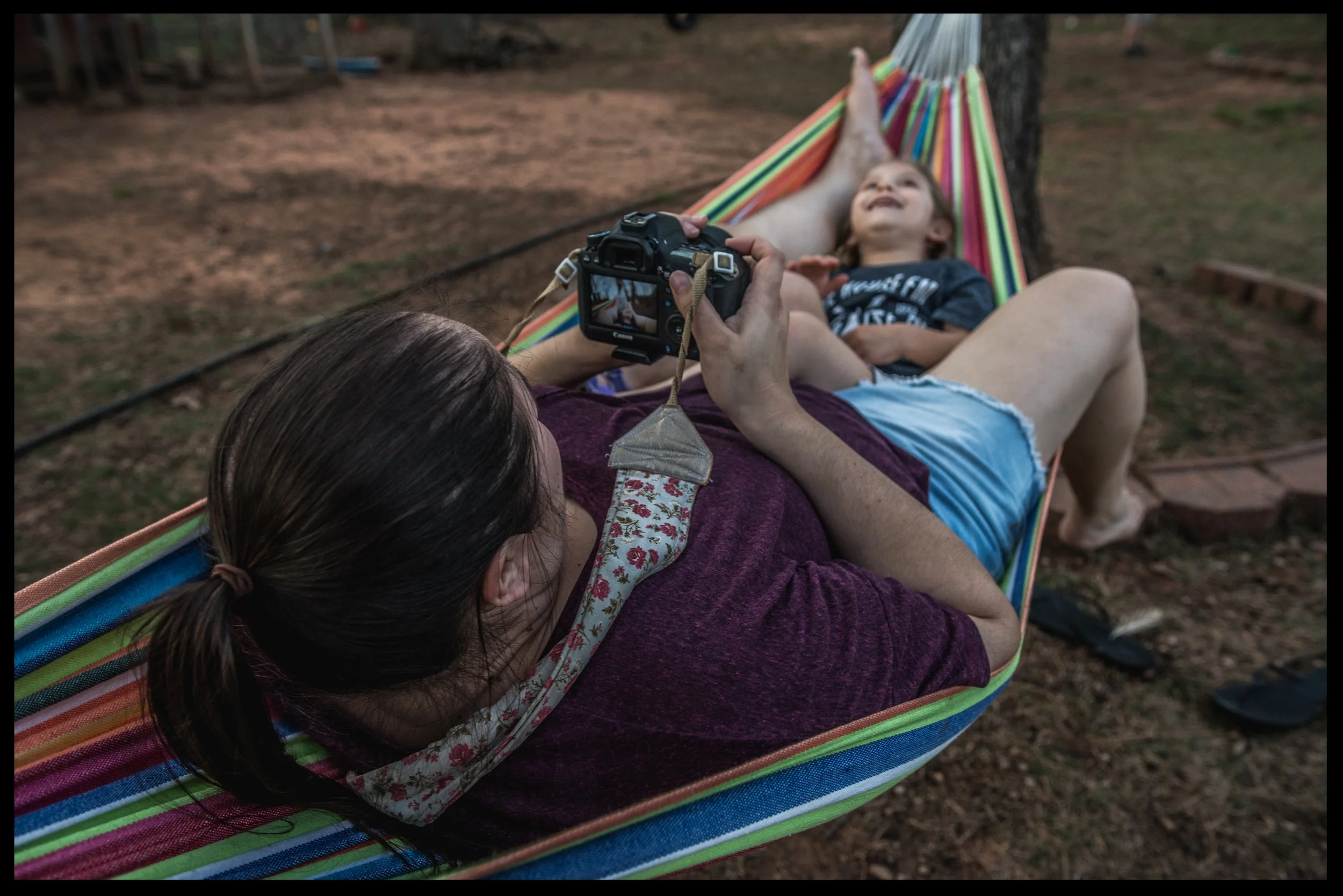 Mother taking a photo of her daughter in a hammock, color