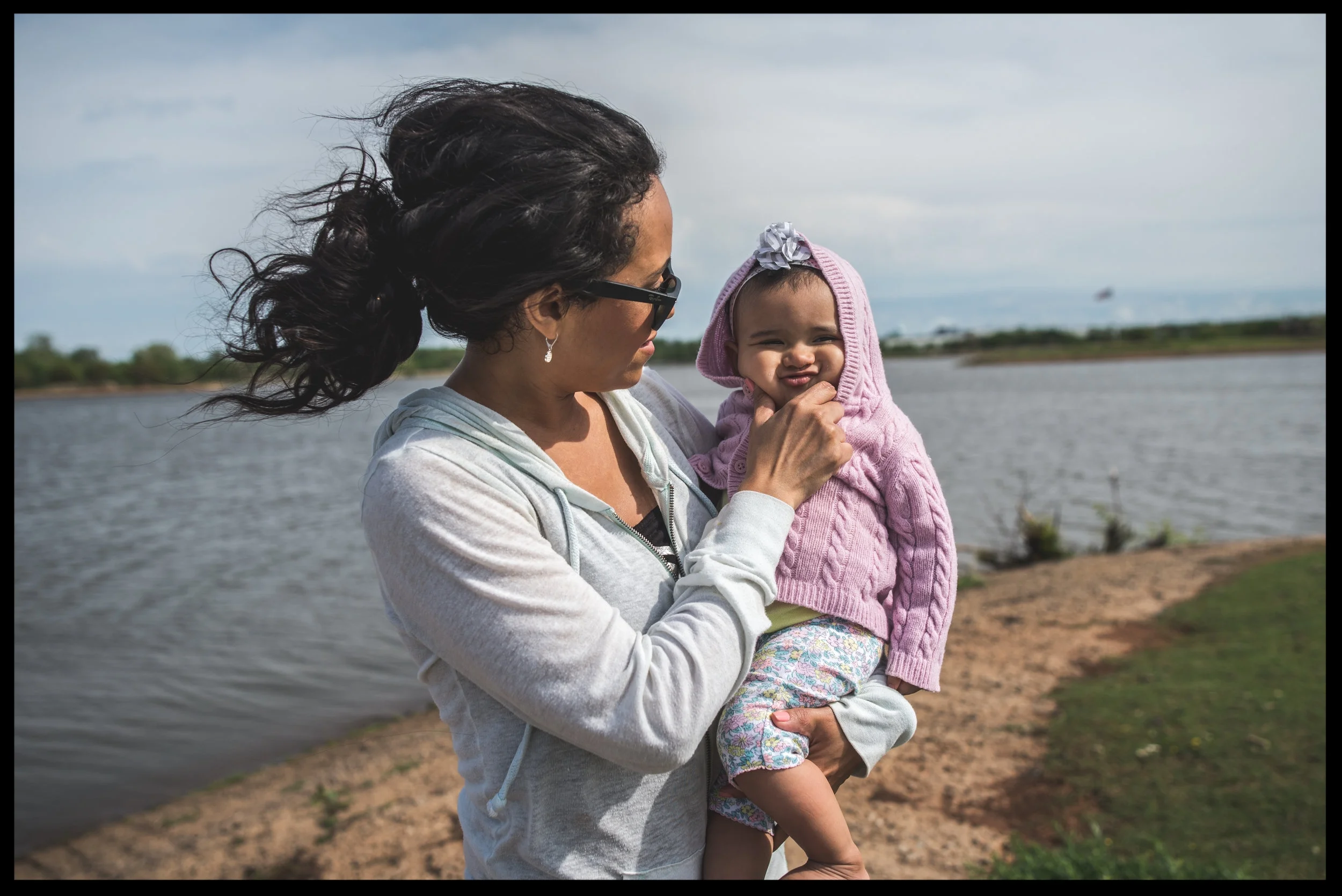 Mother squishing her baby's little face at the lake, color