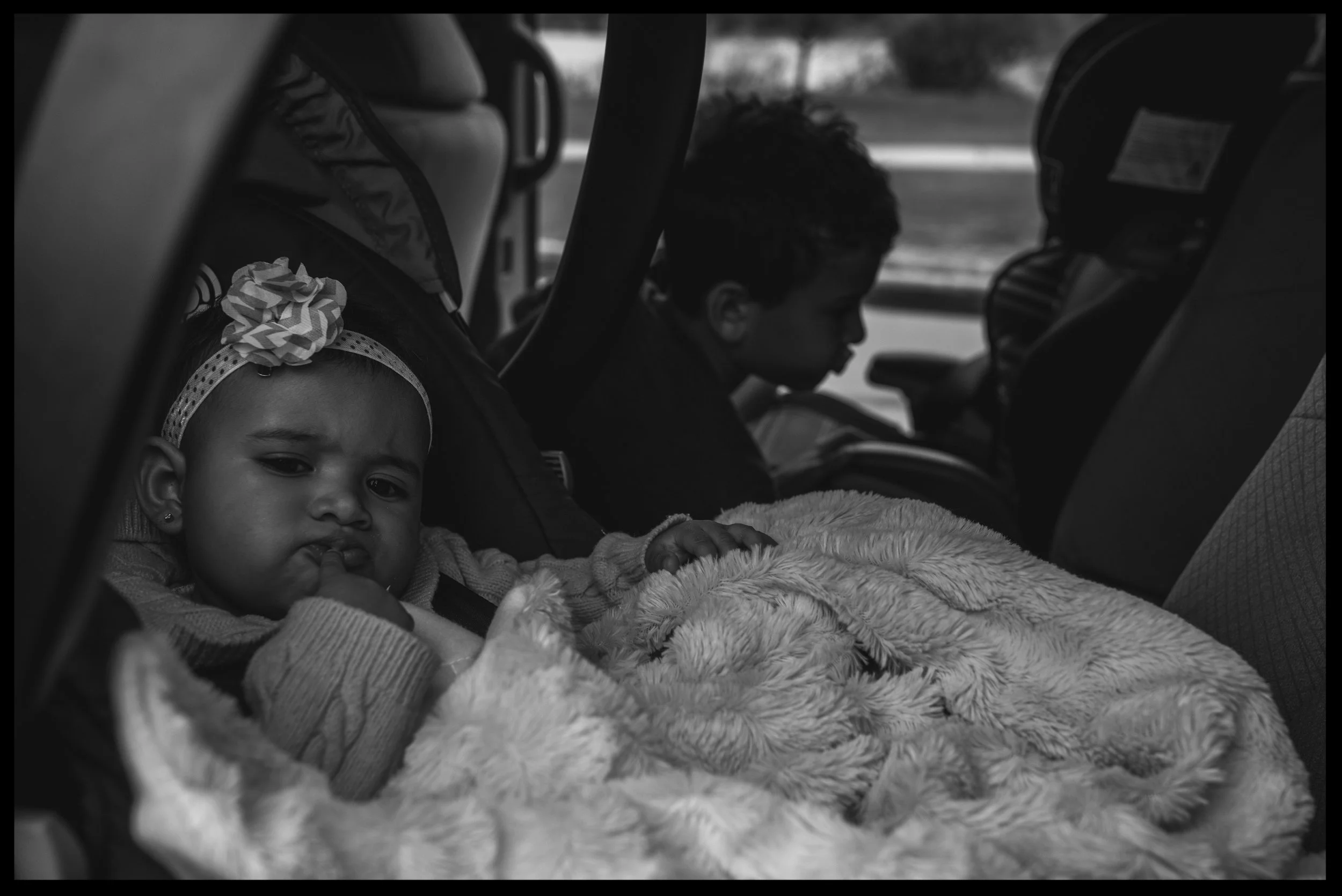 Two kids in the car waiting to go, making cute faces, black and white