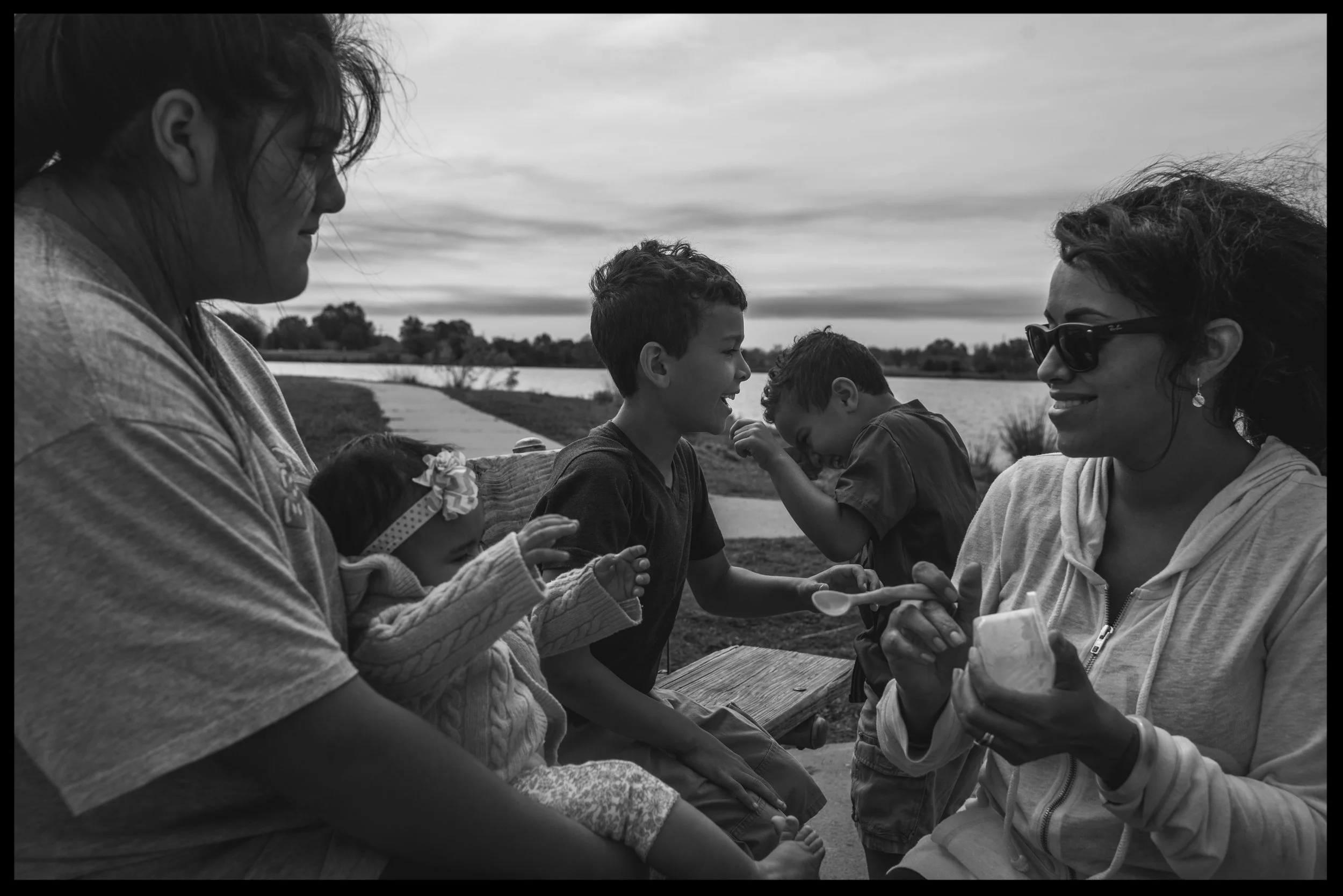 Mom, aunt, and three kids laughing together at the lake, black and white