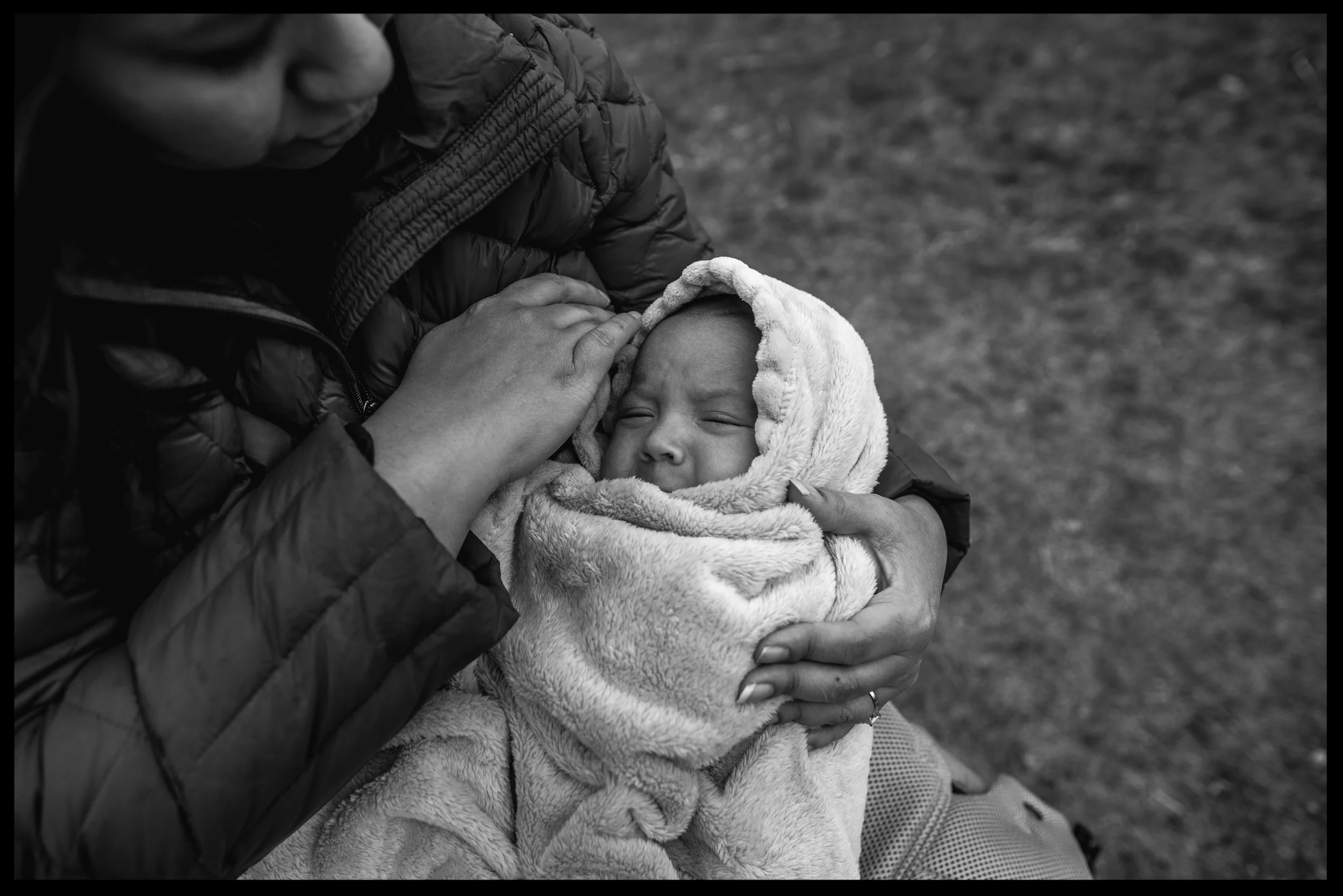 Baby boy bundled up in a blanket with his mother holding him, black and white, Golden, Colorado