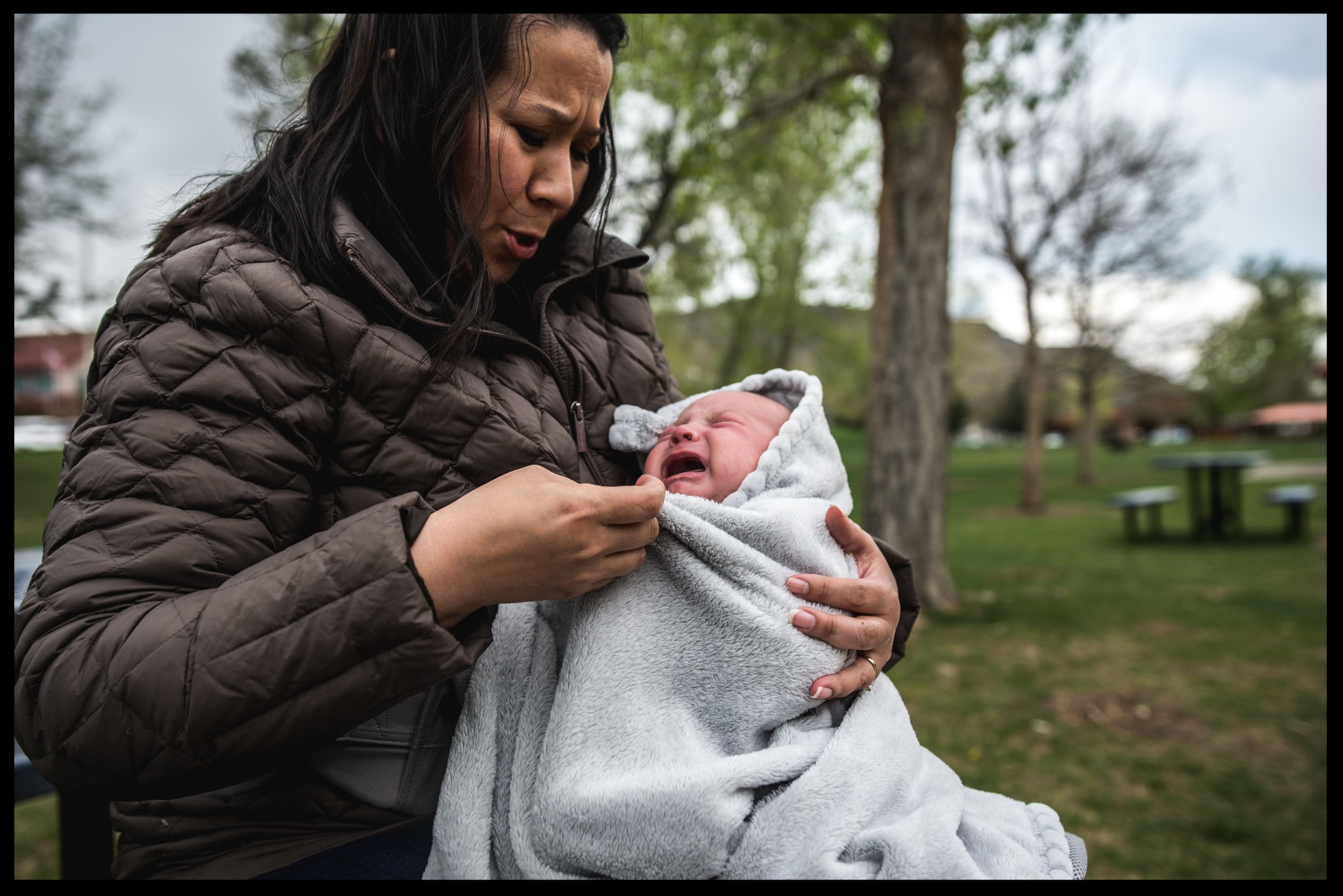 Baby in his mother's arms crying, color, Golden, Colorado