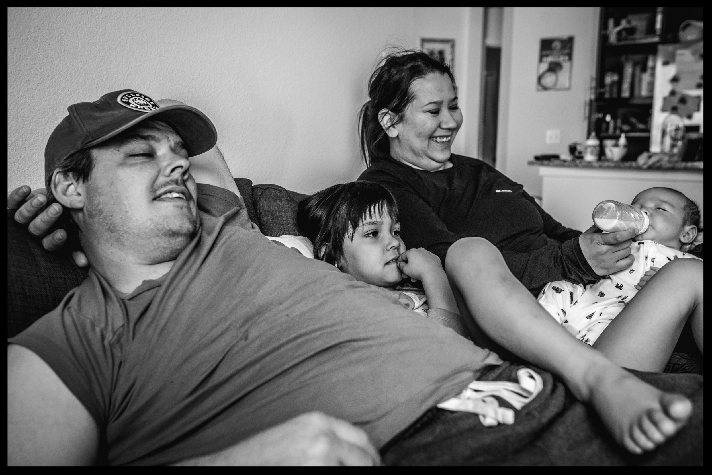 Parents and two kids all cuddling together on the couch, black and white, Lakewood, Colorado