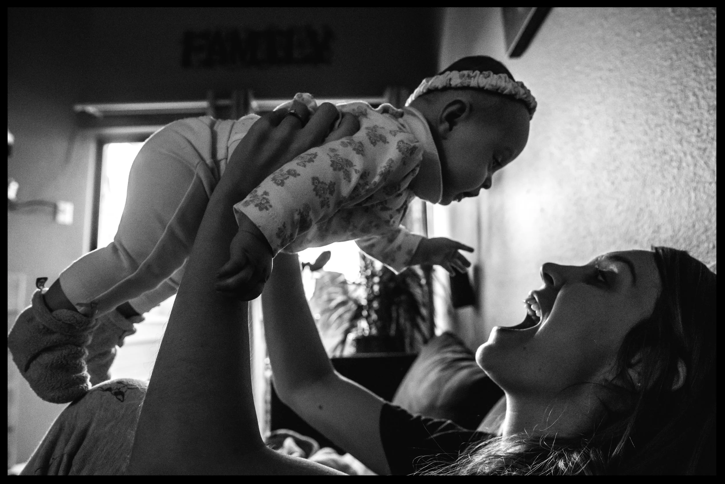 Mother holds baby girl up in the air and smiles, black and white, Aurora, Colorado