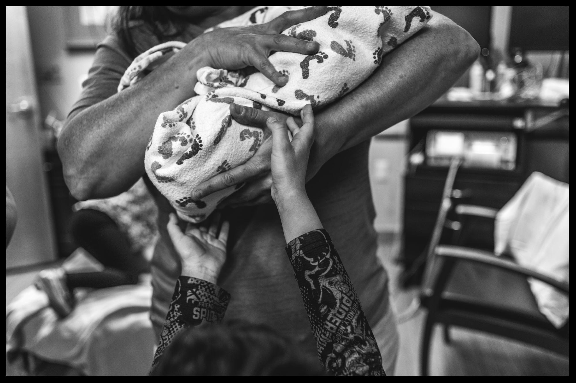 Little boy reaching up to grab his new baby sister, black and white, Stillwater, OK