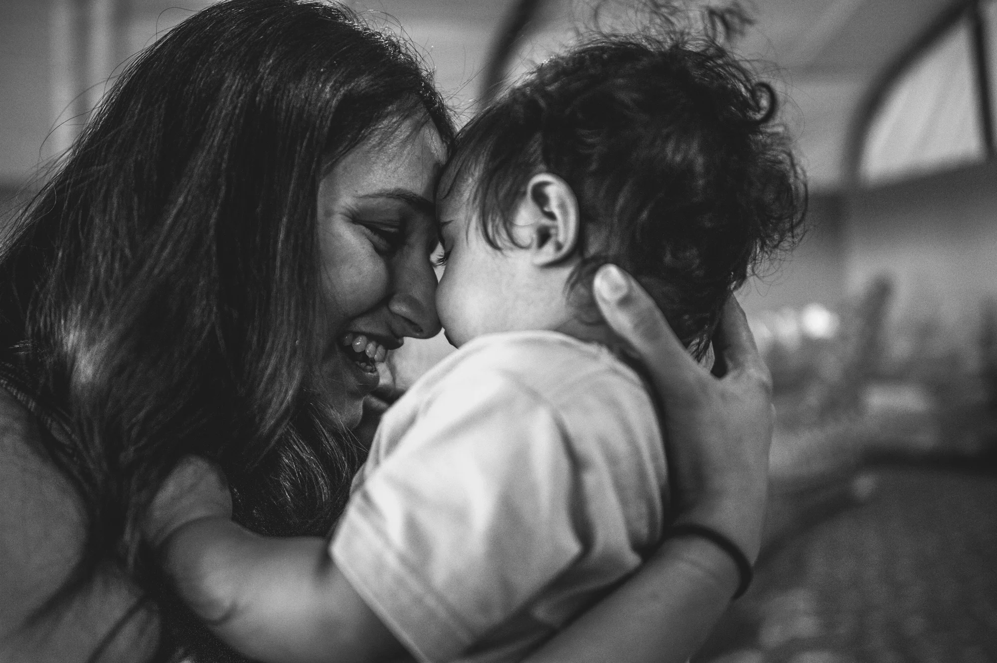 Mother puts her forehead to her baby boy's head on his one year birthday, black and white
