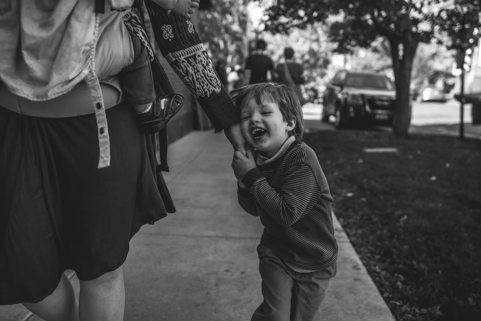 Little boy holding on to his mother's hand and smiling with joy, Pearl Street Farmer's Market, Denver, Colorado, black and white