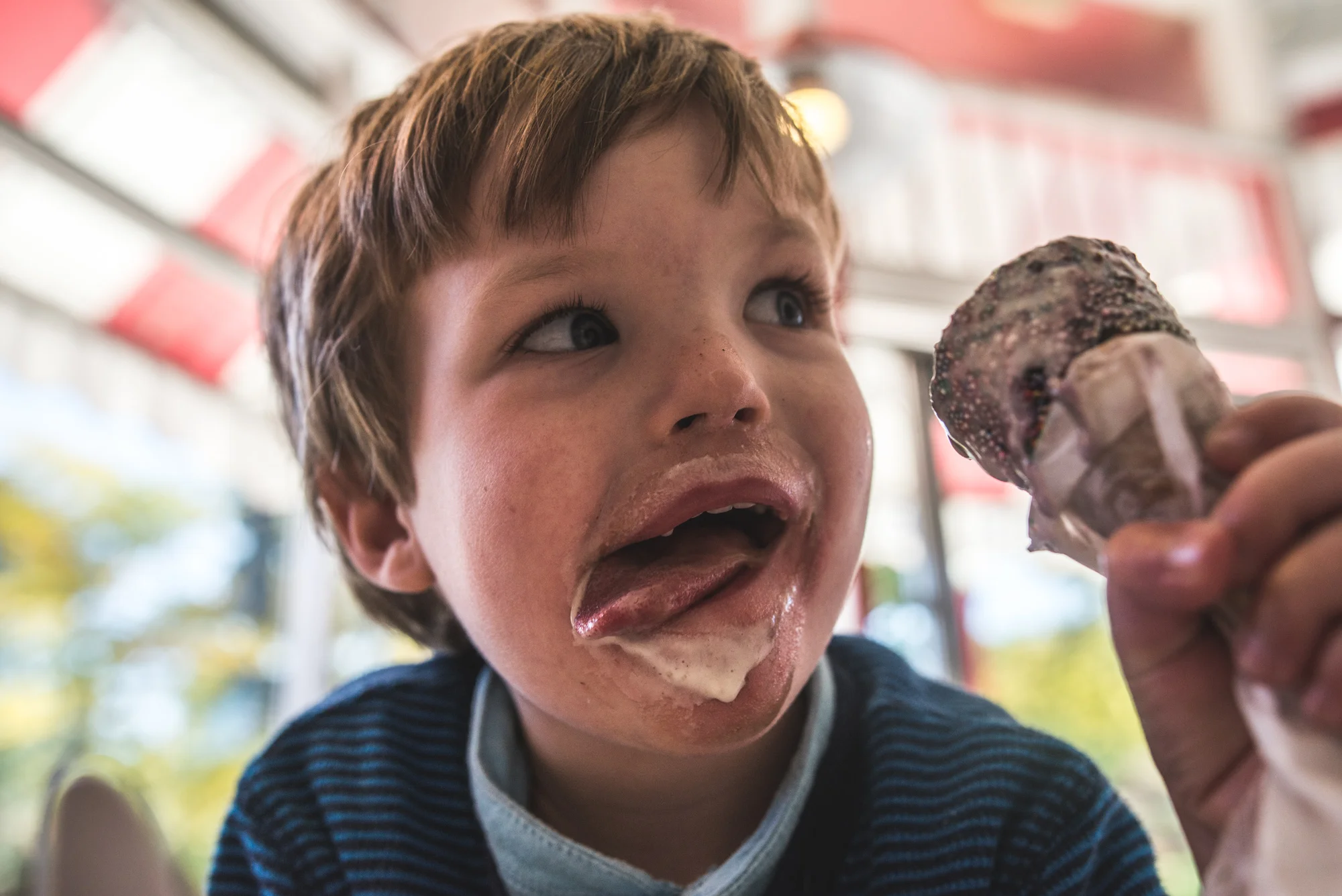 Little boy with ice cream all over his face, trying to lick it off, Denver, Colorado, color