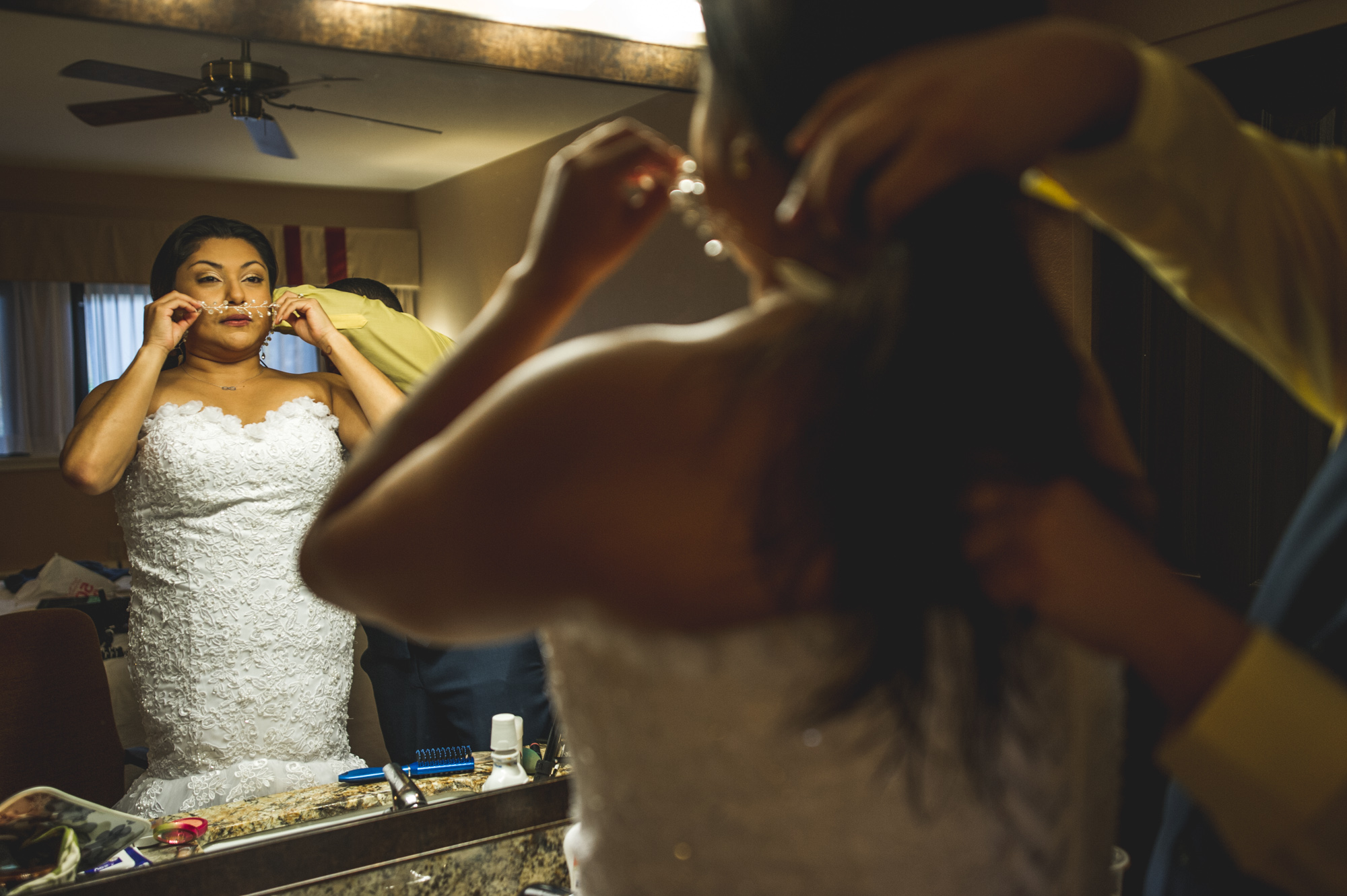 Groom helps his bride put on her head piece as the bride looks in the mirror, Estes Park, Colorado, color
