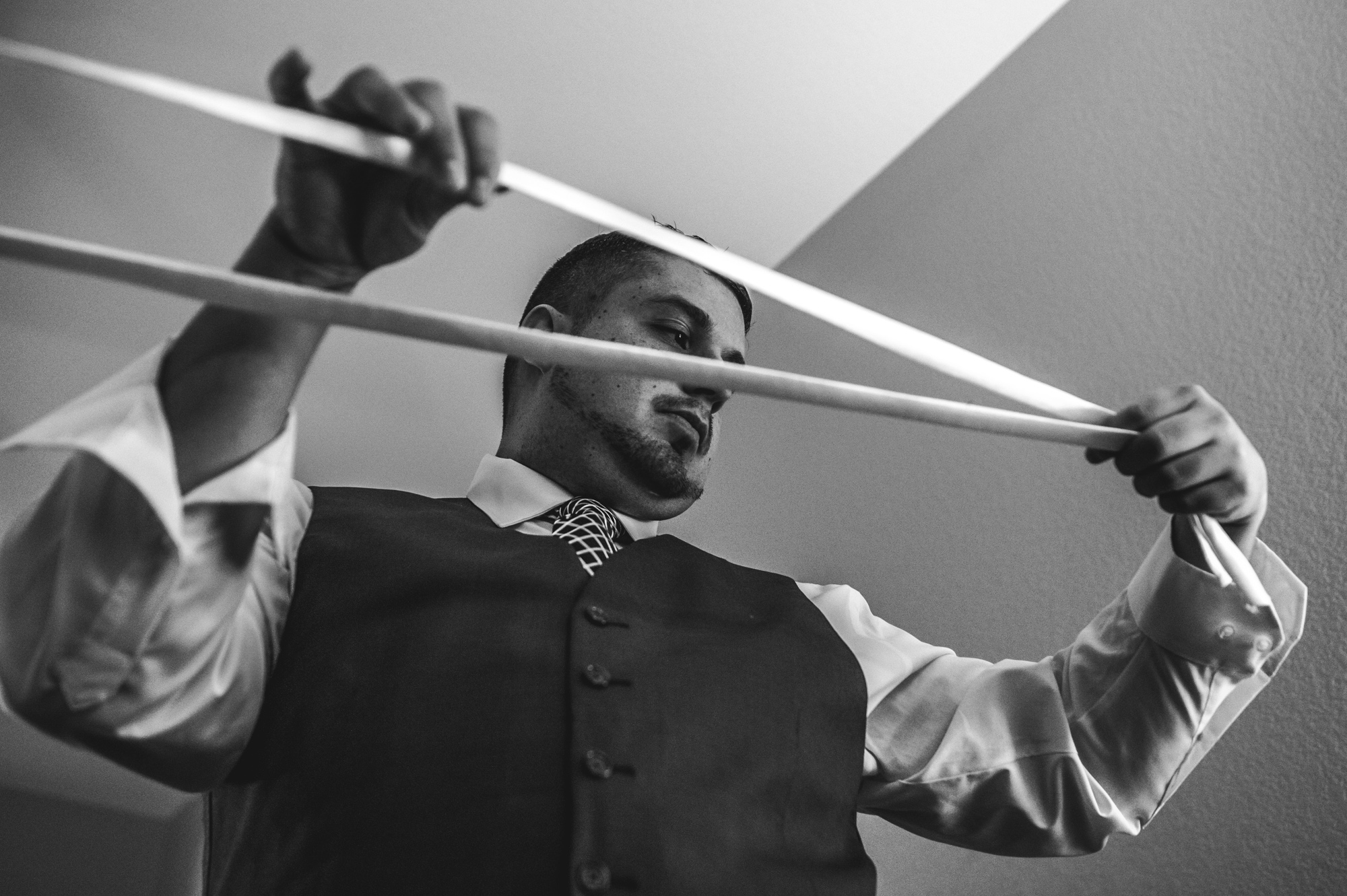 Groom holds up the strings to tie his bride's wedding dress, Estes Park, Colorado, black and white