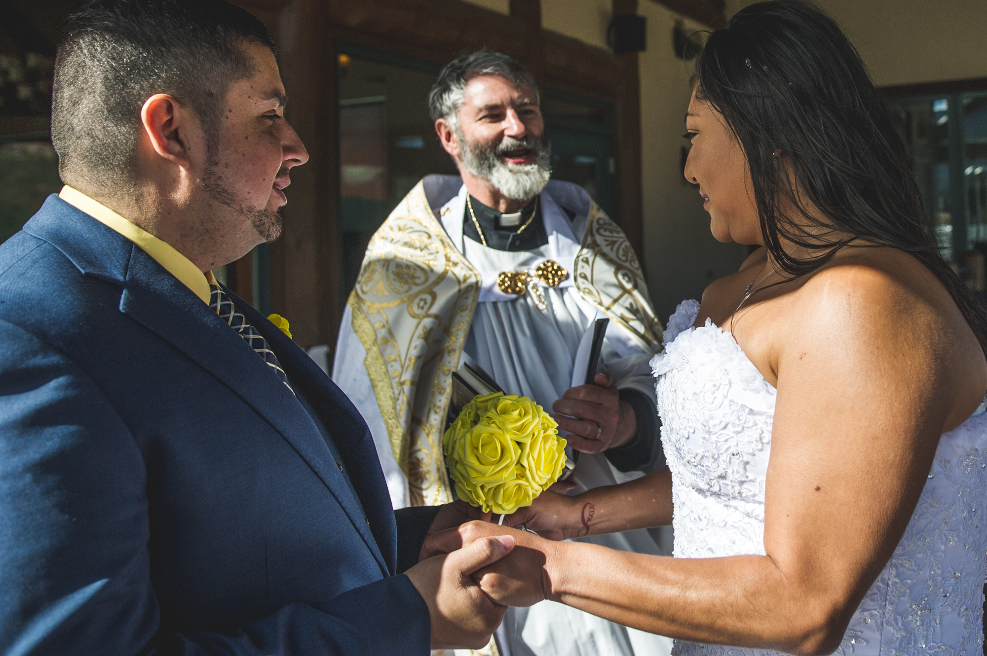 Bride and groom hold hands during their ceremony, Estes Park, CO, color