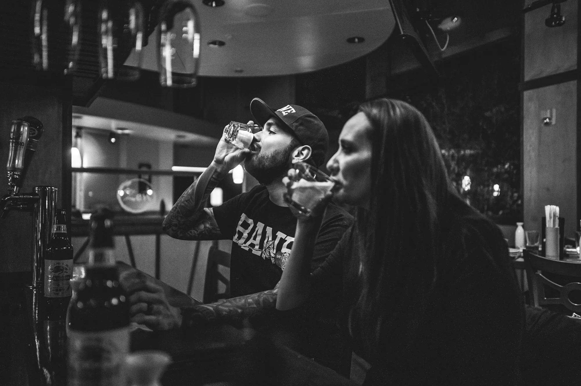 Couple in a sushi restaurant takes saki bombs, black and white, Stapleton, Colorado