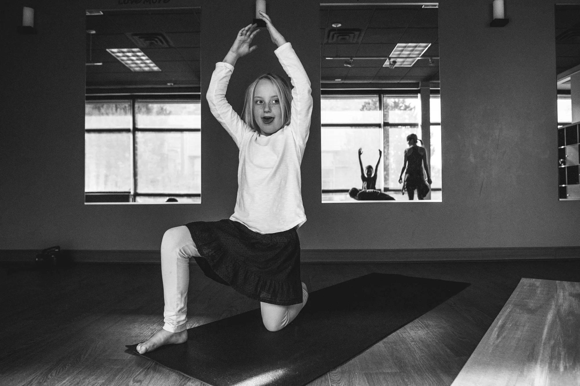 A young girl strikes a yoga pose during a yoga class for neurodiverse students in Highlands Ranch, Colorado, black and white