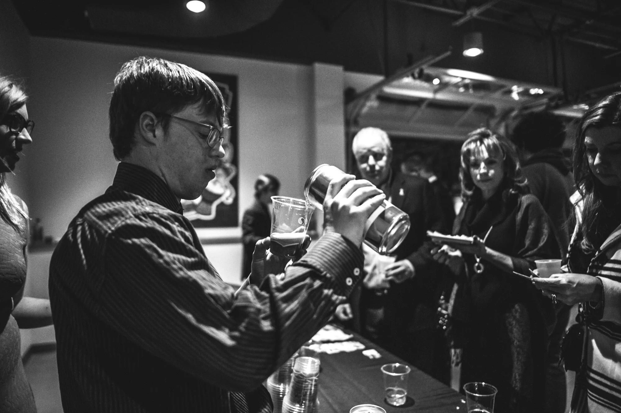 An employee of Brewability Lab pours a beer for guests at the Autism Society's Winter Fundraiser at the Vehicle Vault in Parker, CO. Photo in black and white.