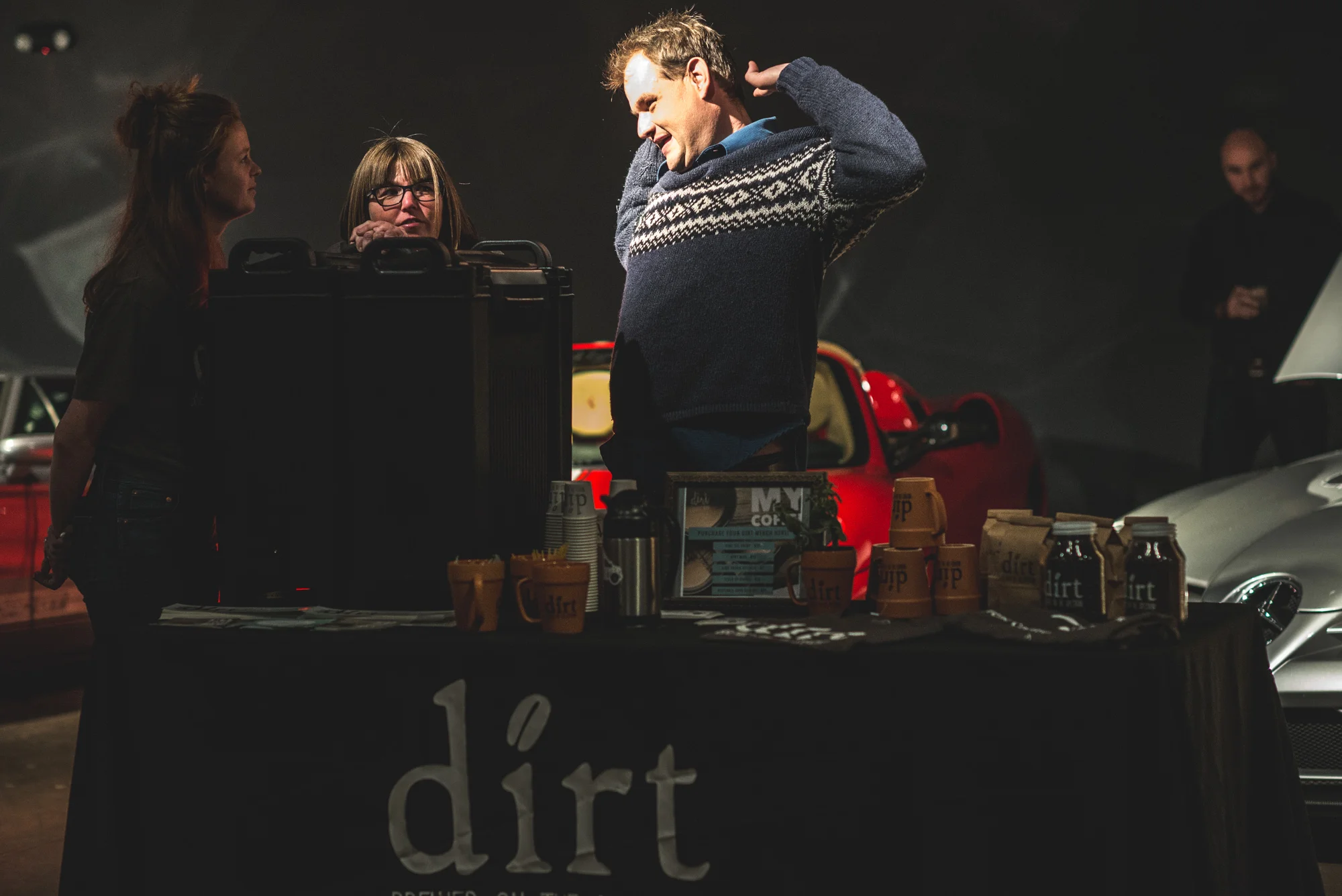 A Dirt Coffee employee stretches his arms as the light shines on him at the Vehicle Vault in Parker, Colorado. Photo in color.