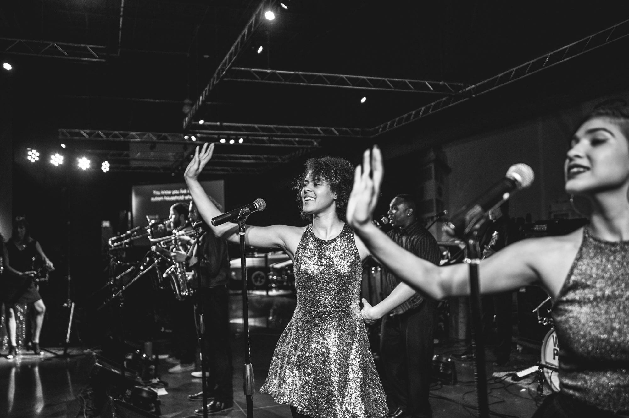 The vocalists of the Wash Park Band do a choreographed dance move during their performance at the Autism Society's Winter Fundraiser. Black and white.