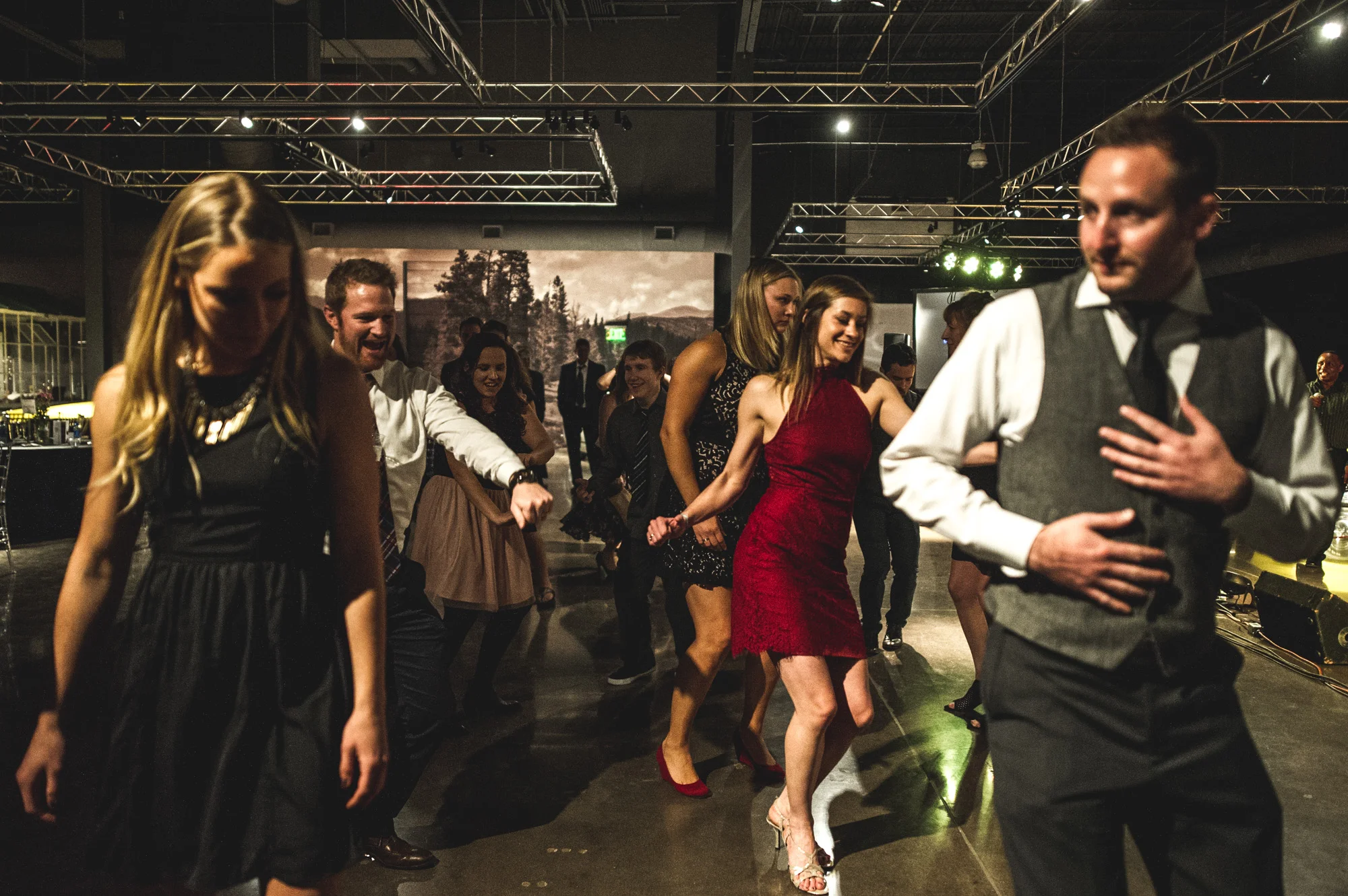 A group of guests at the Autism Society Winter Fundraiser at the Vehicle Vault do a line dance to the music of the Wash Park Band. Photo in color.