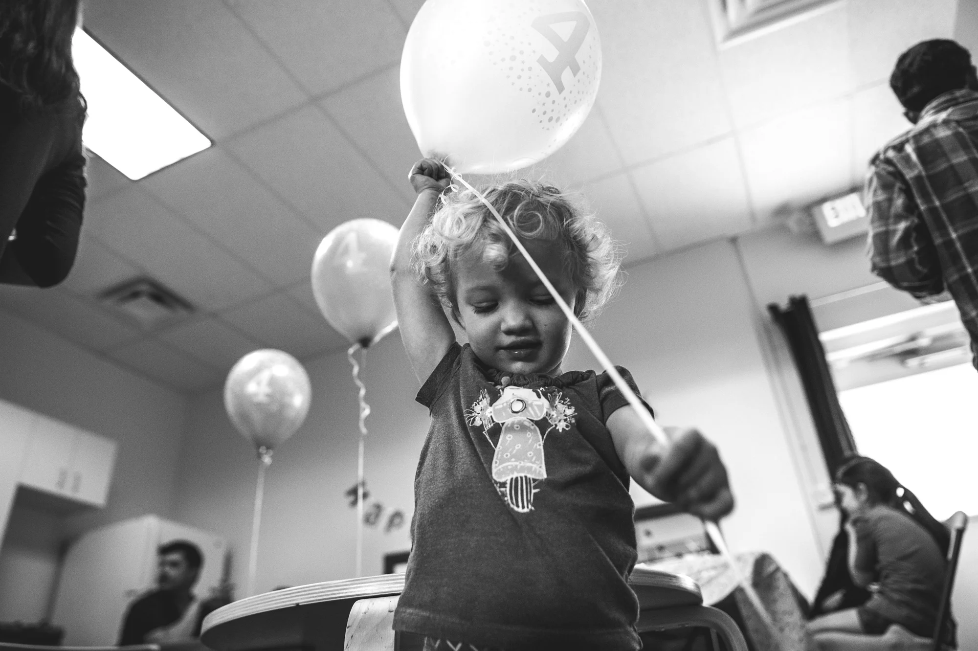 Black and white photo of a young girl playing with a balloon at a birthday party at Family Connections Thera-play kids' gym in Littleton, Colorado